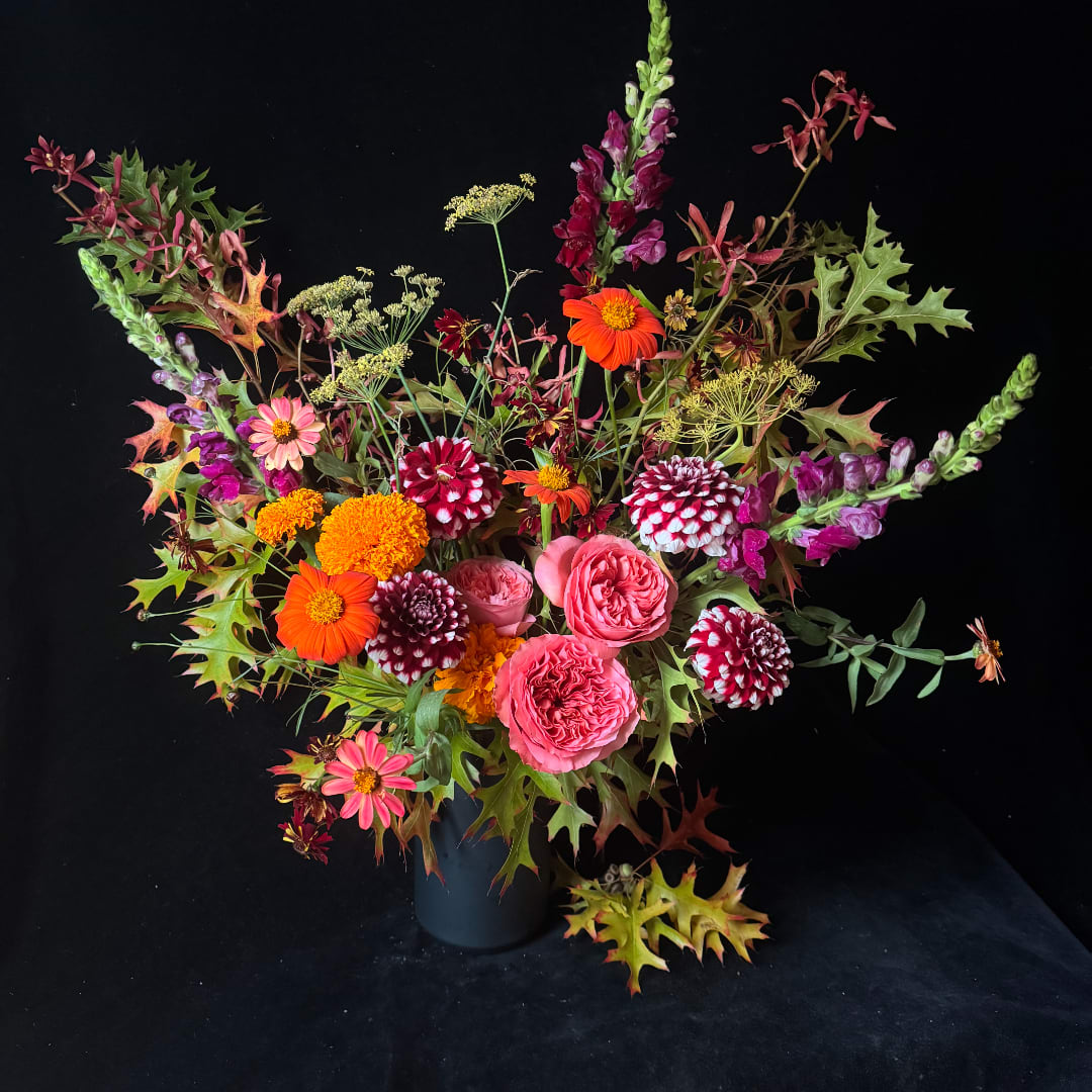 Colorful mixed bouquet in a dark vase with pink, orange, and burgundy blooms