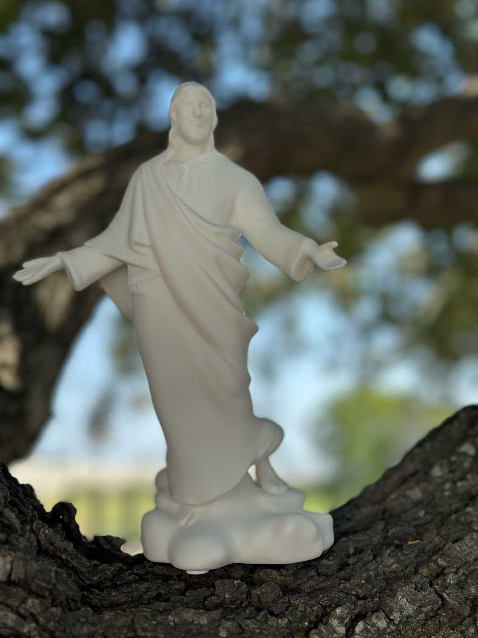 White religious statue of Jesus standing on a tree branch