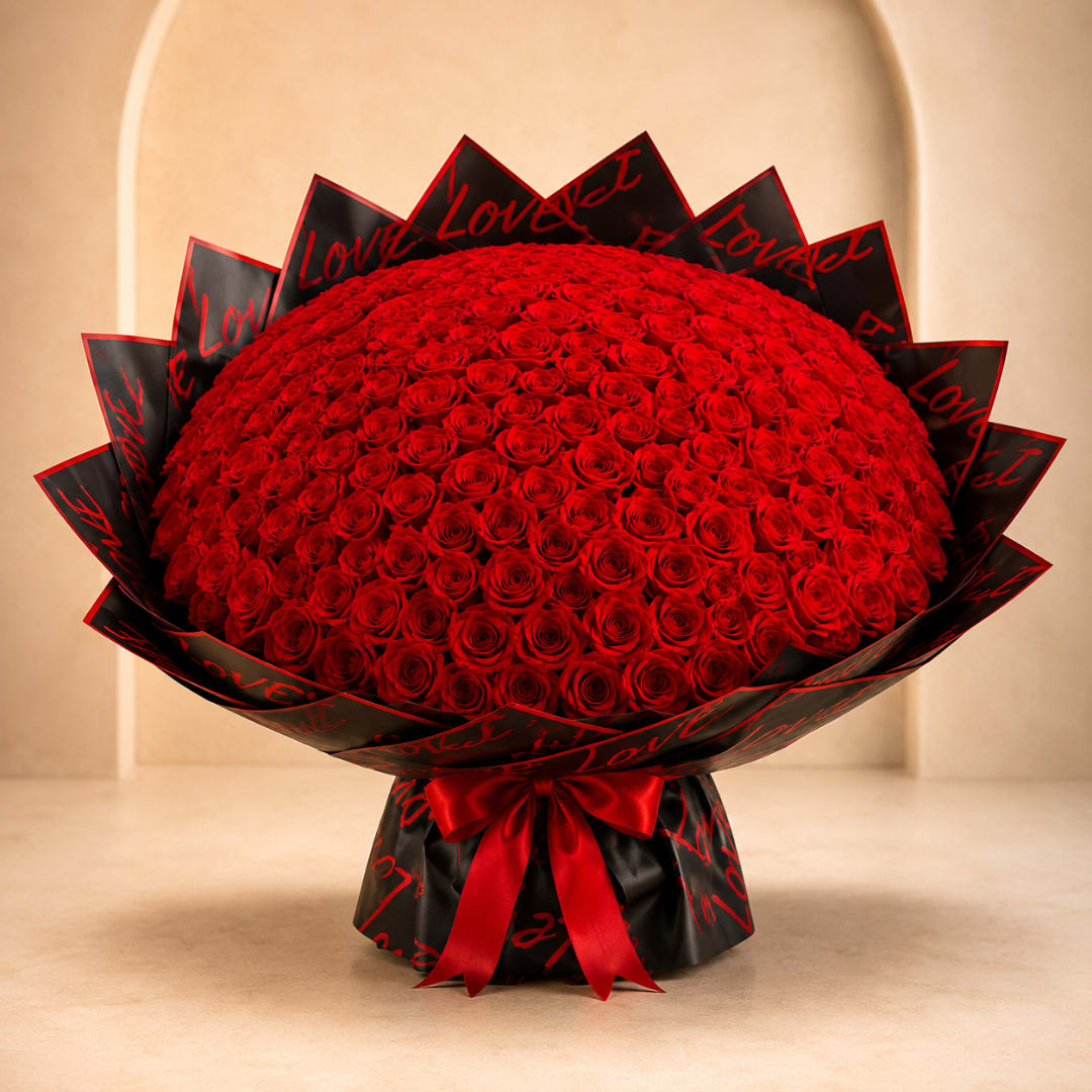 Large bouquet of red roses wrapped in black paper with red lettering and a red ribbon
