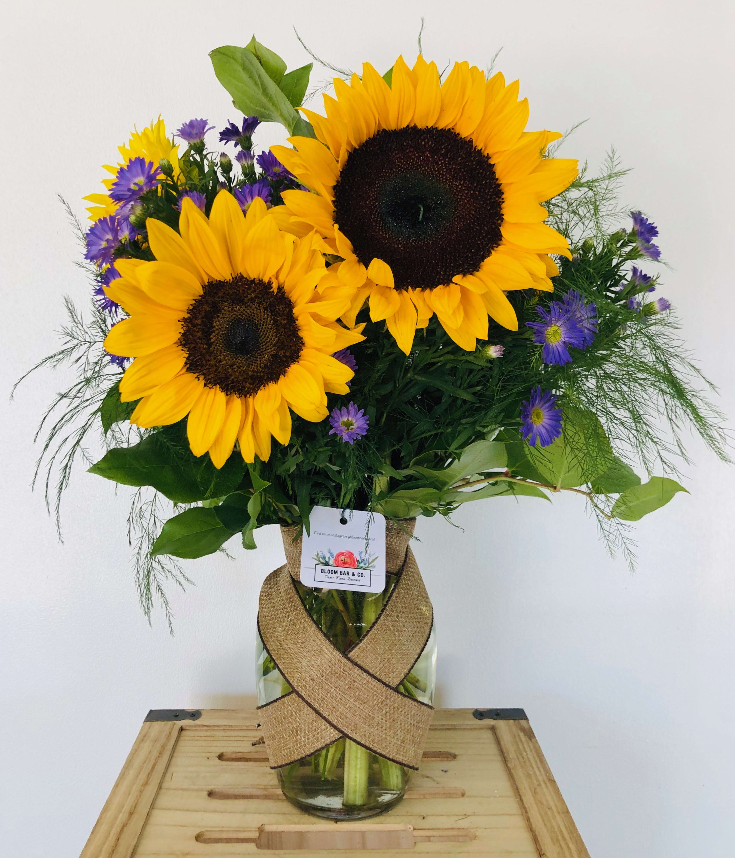 The Bee Stinger - Nothing lights up a room like the golden glow of sunflowers and bright purple monte casino asters, gathered up and presented in a big bouquet. Upgrade to deluxe or premium to get a sparkly little bumblebee and really add some zing!
