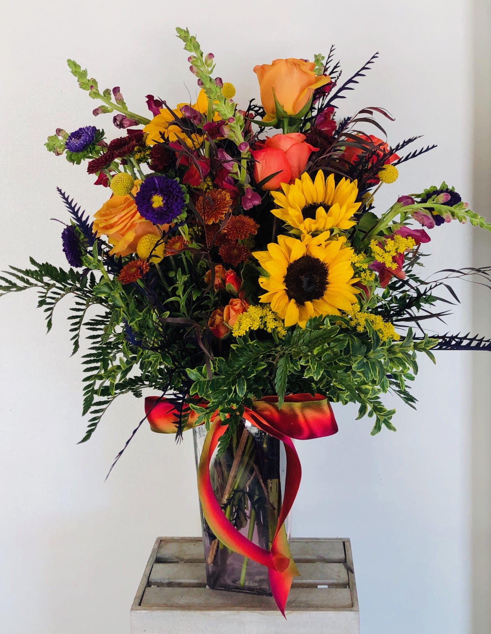 Colorful bouquet with sunflowers, roses, and a glass vase