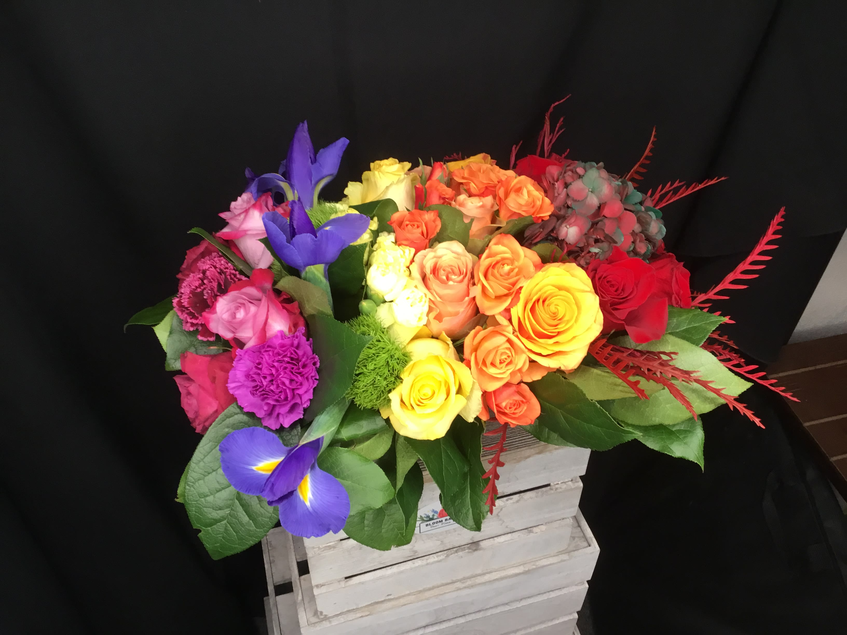 Colorful bouquet of roses and irises in a white crate