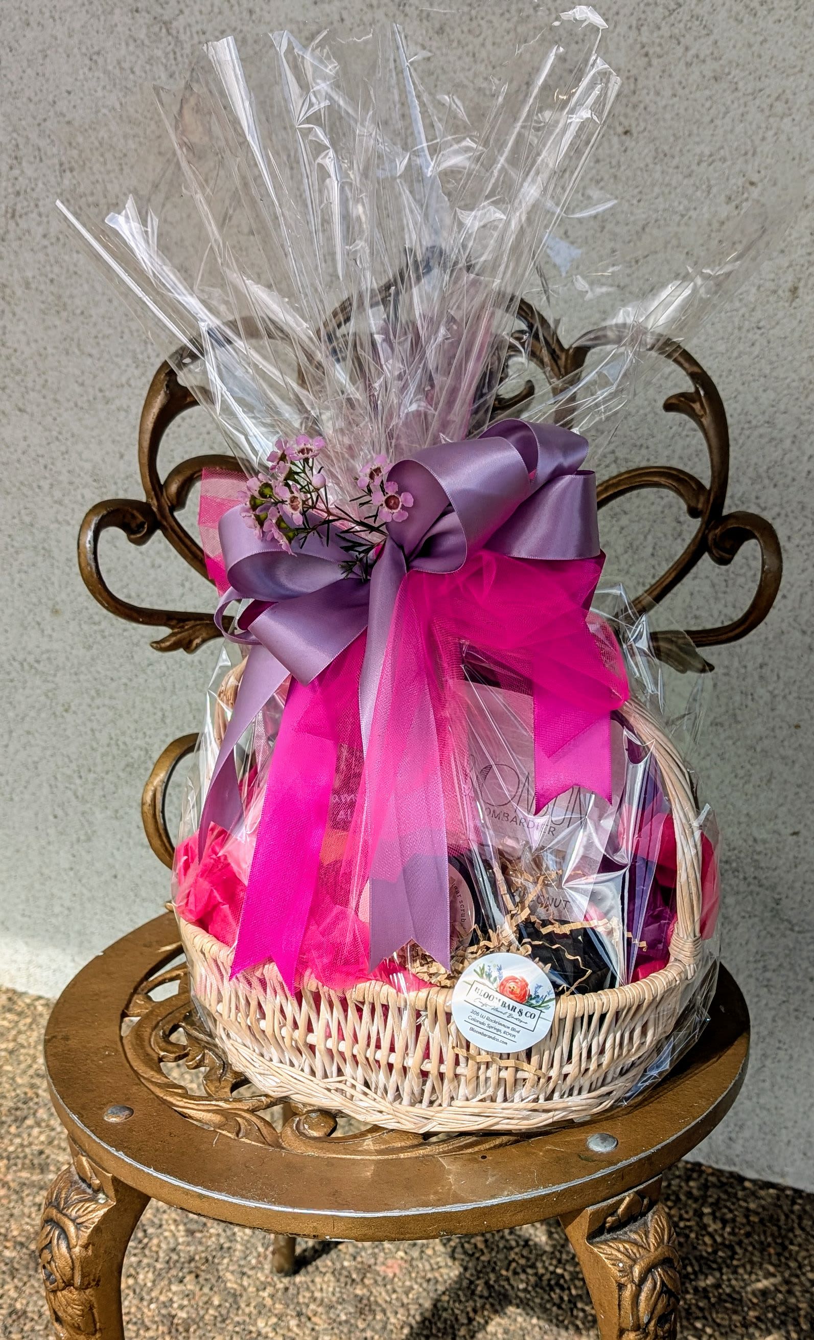 Gift basket wrapped in clear cellophane with pink and purple ribbon