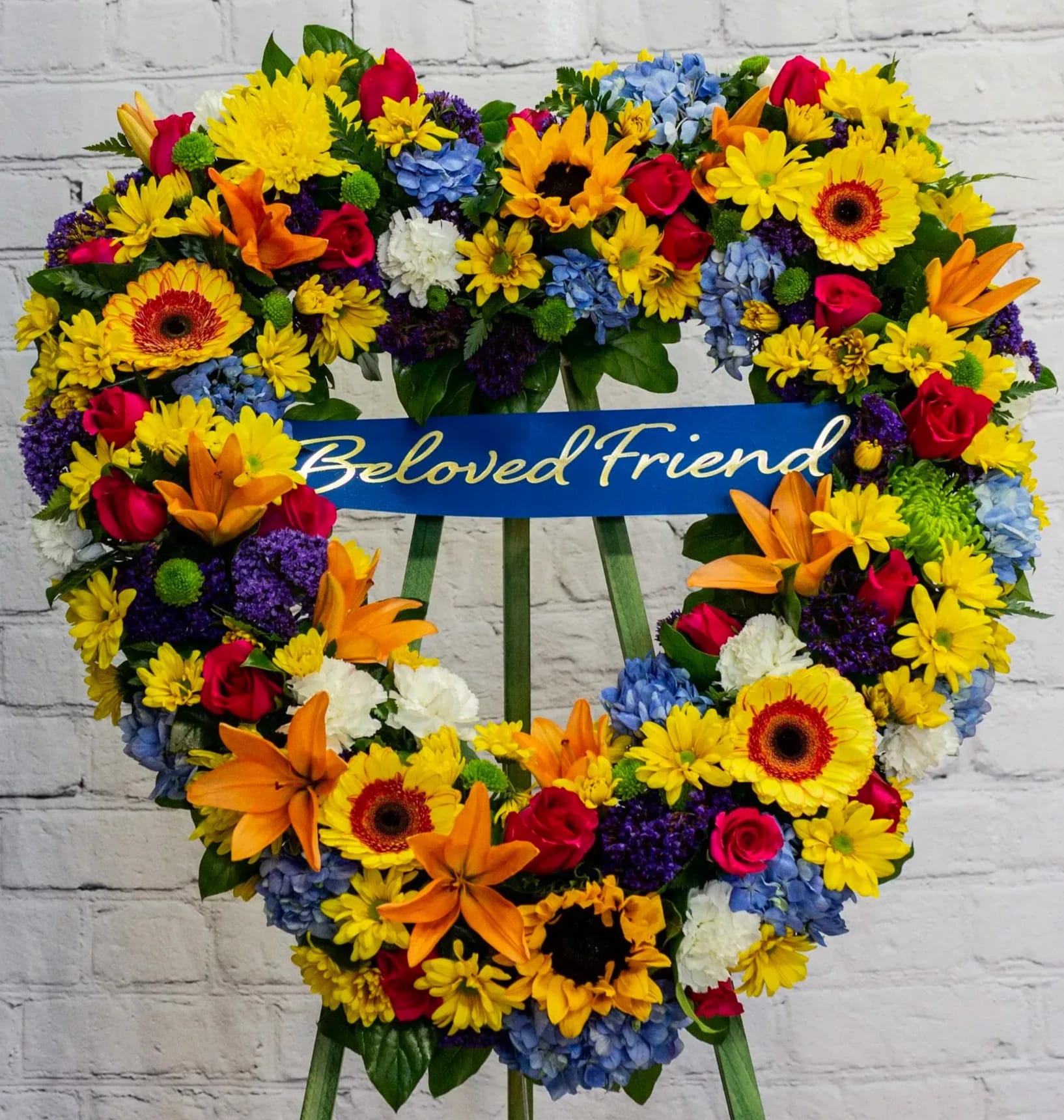 Heart-shaped floral wreath with a "Beloved Friend" ribbon
