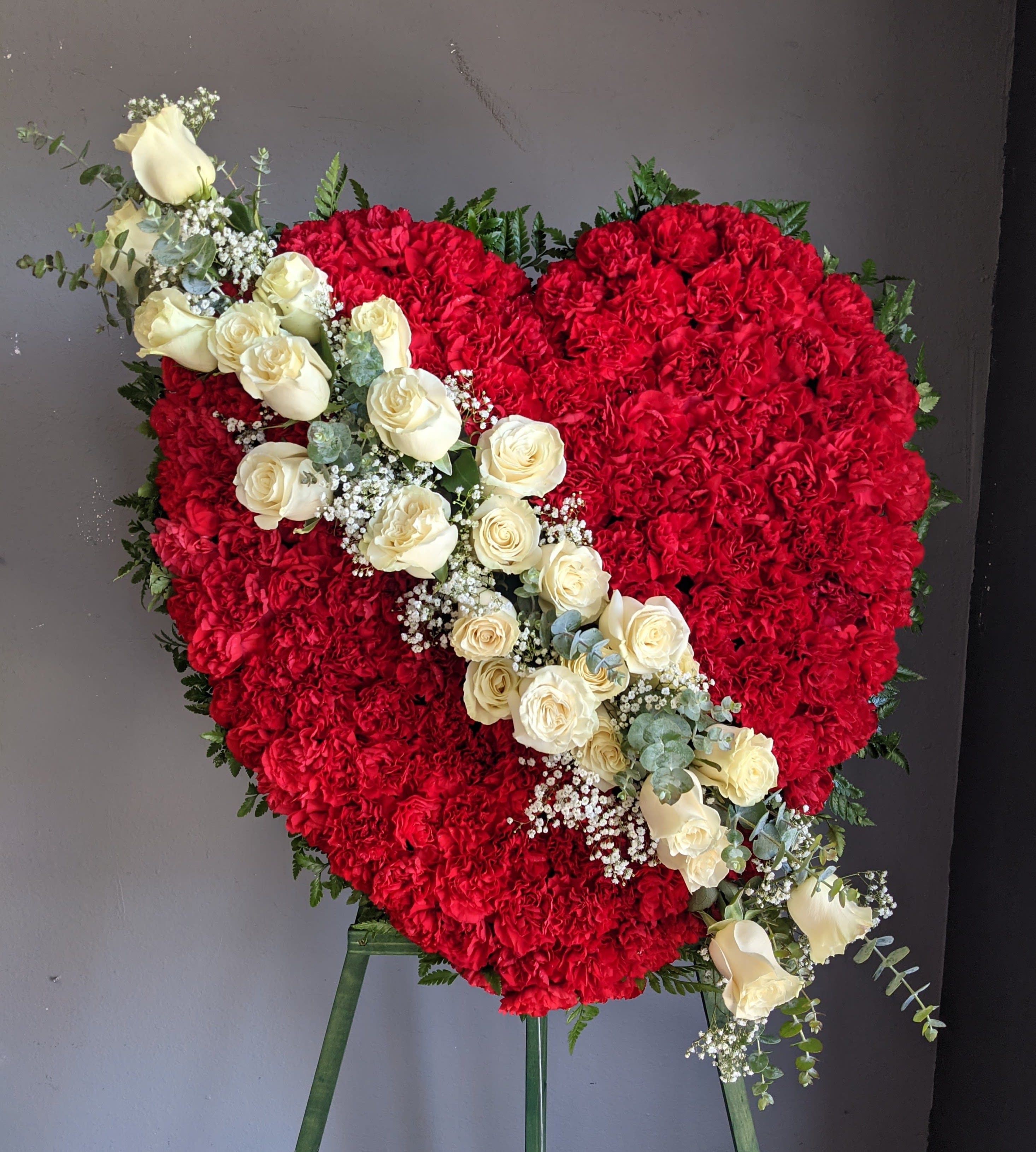 Heart-shaped red floral arrangement with a diagonal spray of white roses