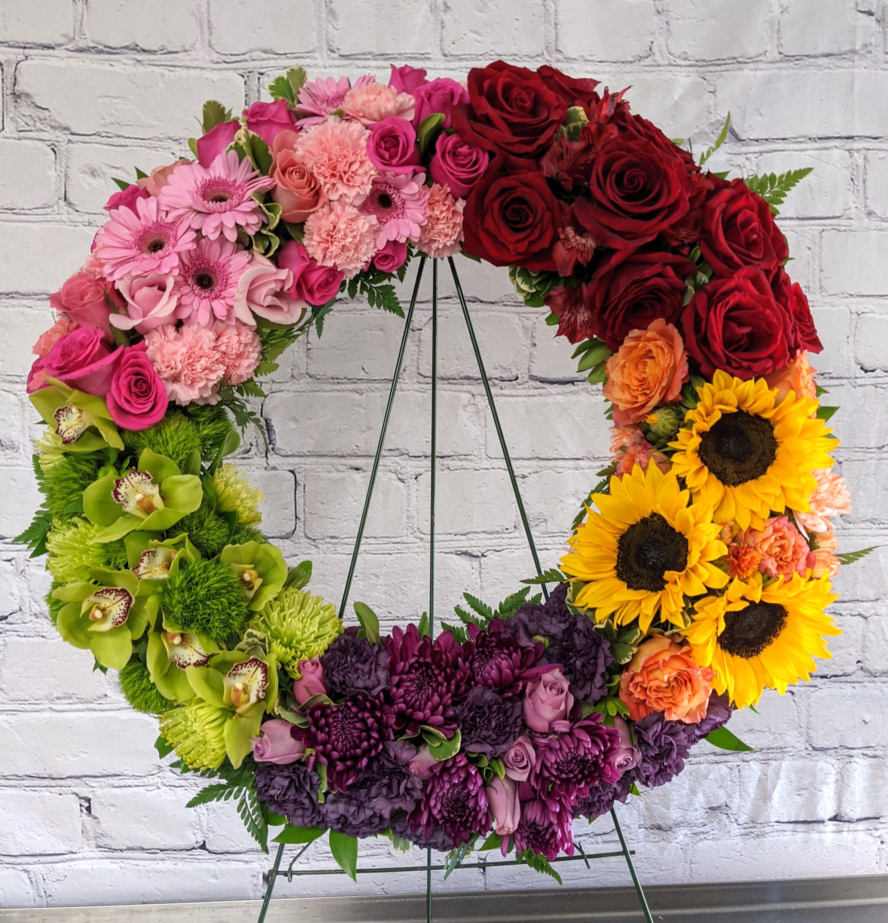 Colorful floral wreath on a metal stand with roses and sunflowers