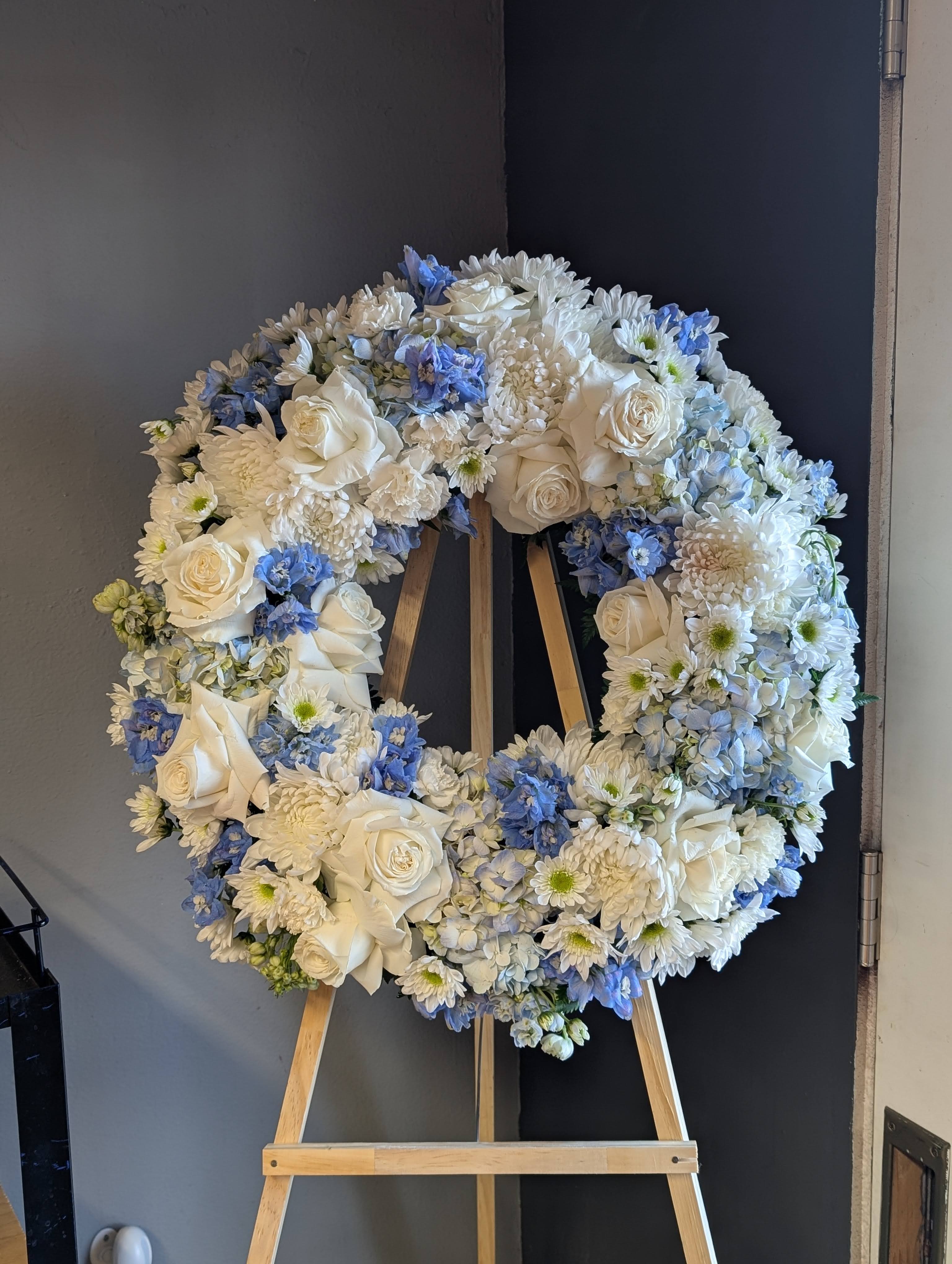White and blue floral wreath on a wooden easel
