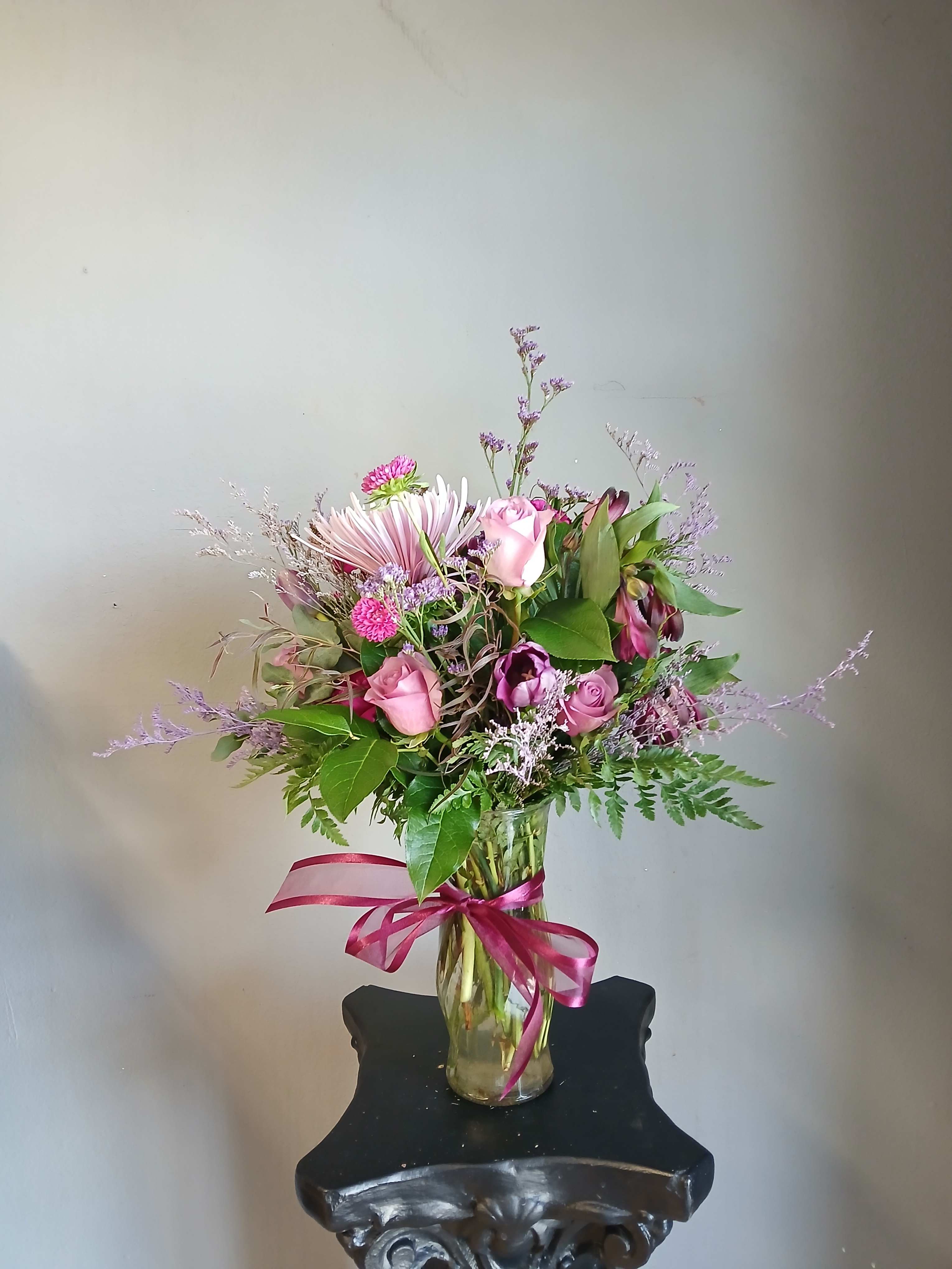 Pink and purple mixed bouquet in a glass vase with a ribbon
