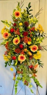 Sundance - Tall easel spray of warm gerbera daisies, mums, Bells of Ireland and lush cascading greenery.