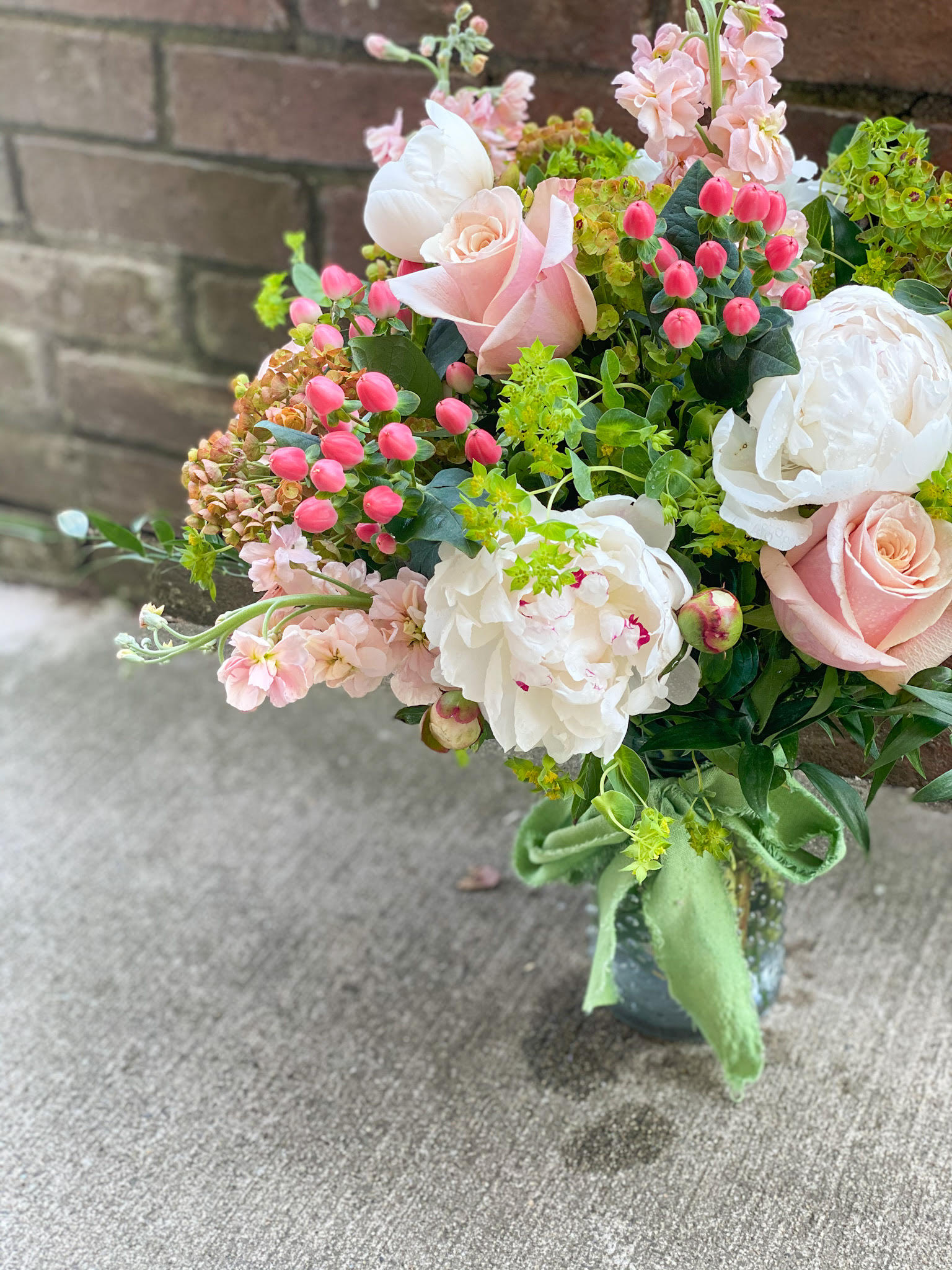 Bouquet of pale pink roses, white peonies, and pink blossoms in a vase