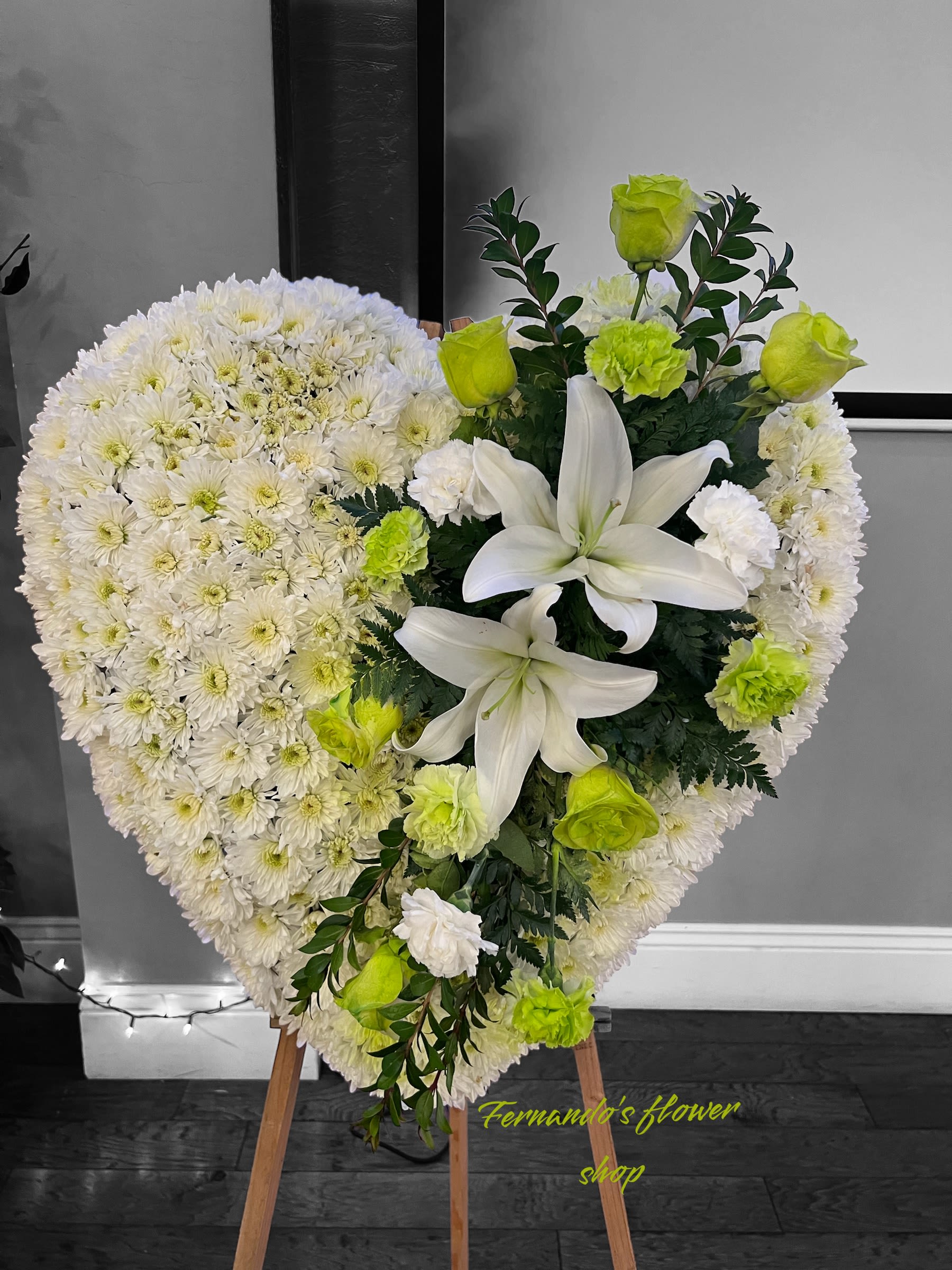 Heart-shaped standing floral arrangement of white flowers with white lilies and green roses.