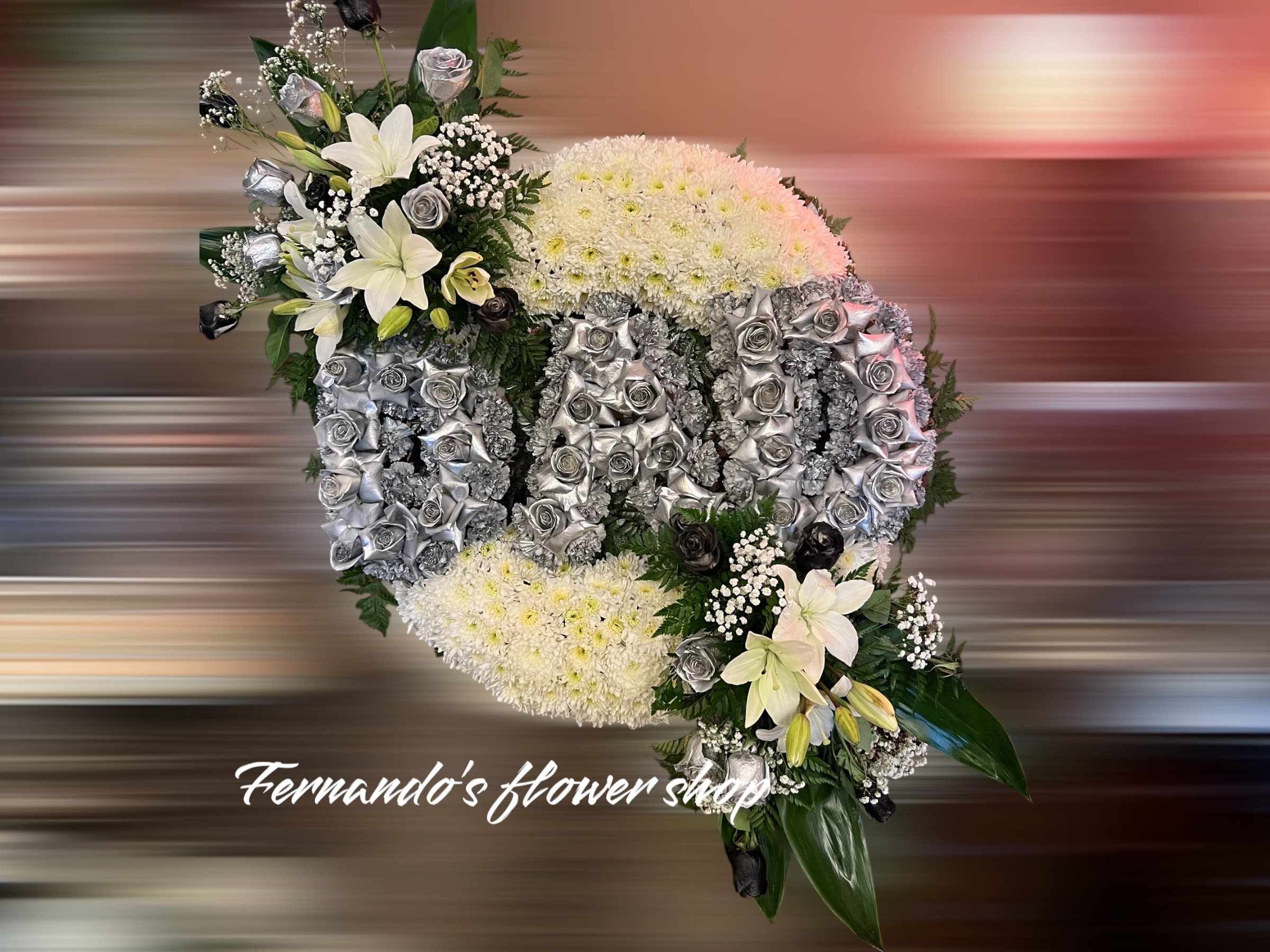 Oval funeral spray reading DAD in silver roses on white mums with white lilies and black accents.