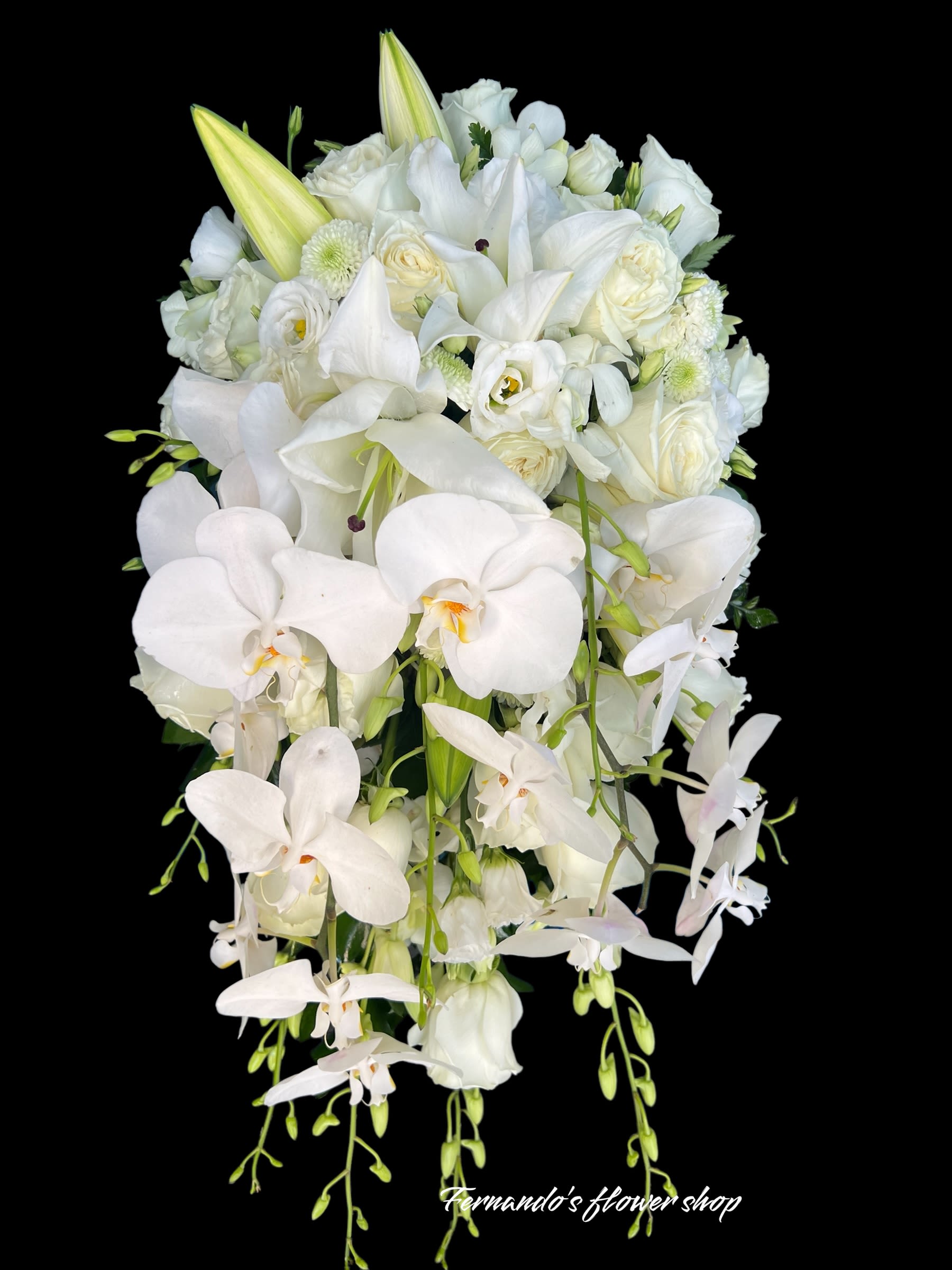 Cascading white bouquet with orchids, lilies, and roses against a black background