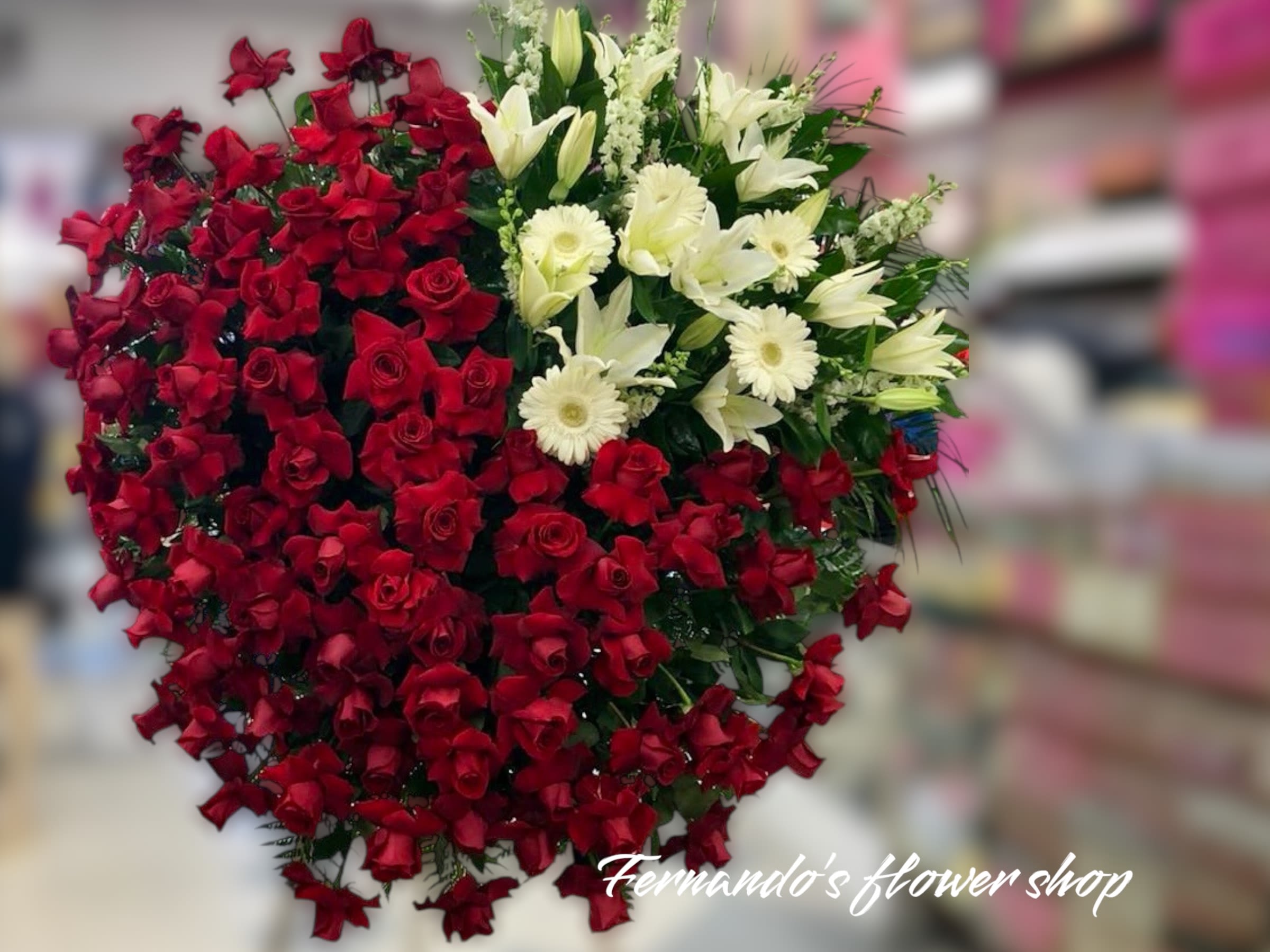 Large heart-shaped arrangement of red roses with white lilies and gerberas on one side