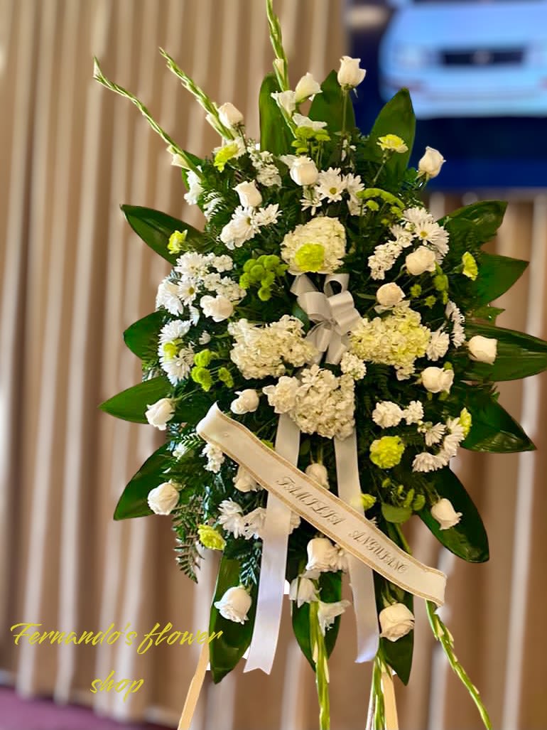 Tall standing spray of white and green flowers with ribbons on an easel