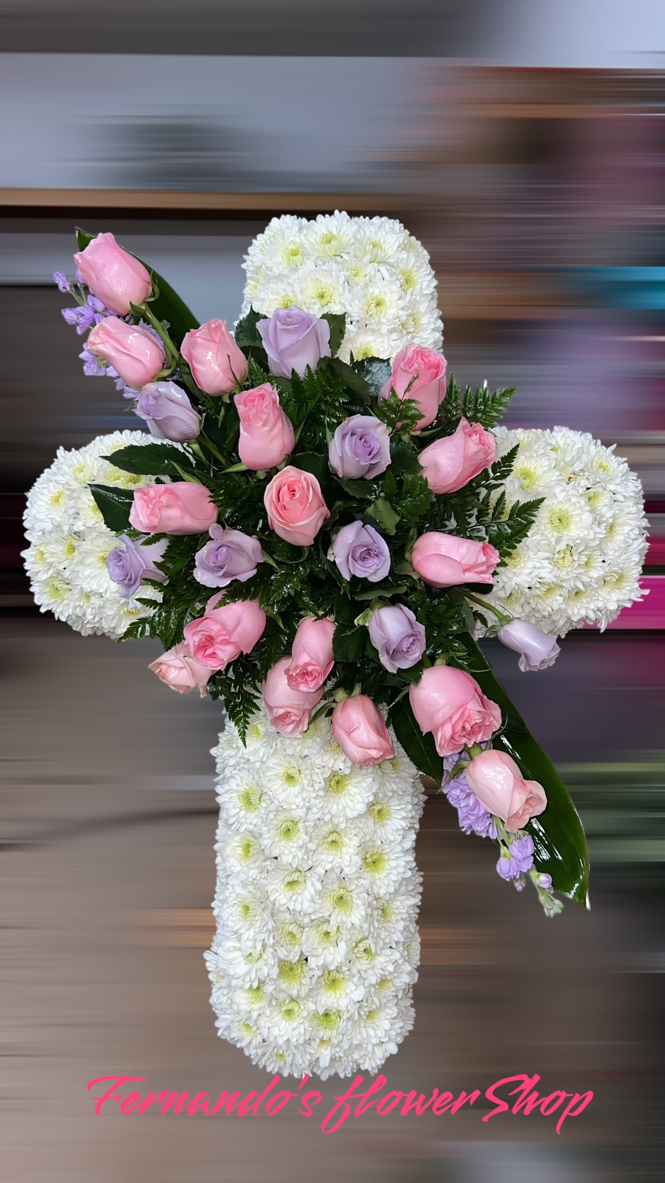 Tall white chrysanthemum cross with pink and lavender roses arranged in the center