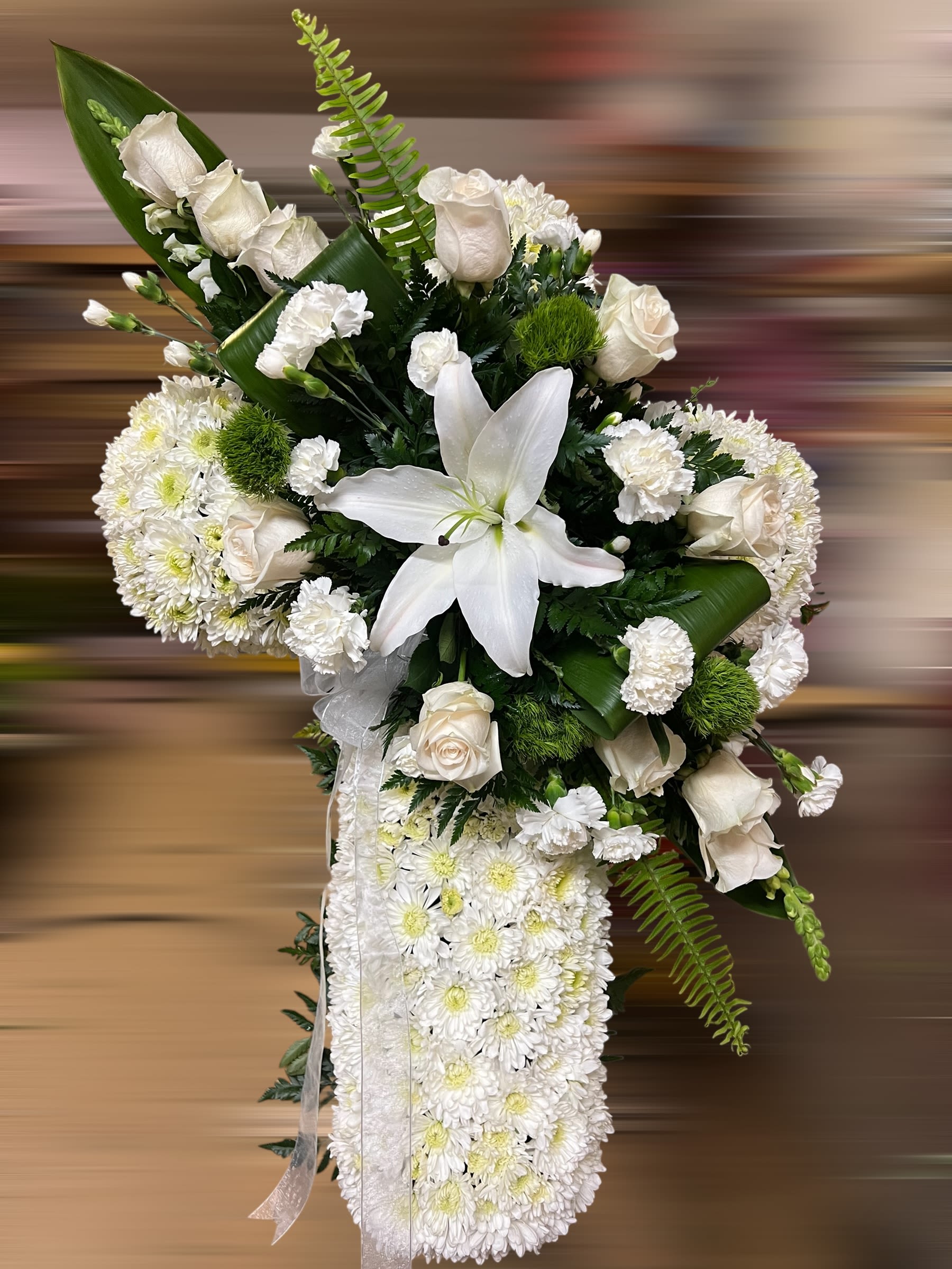 Tall white sympathy spray with roses, lilies, carnations, and cushion of chrysanthemums accented with ribbon