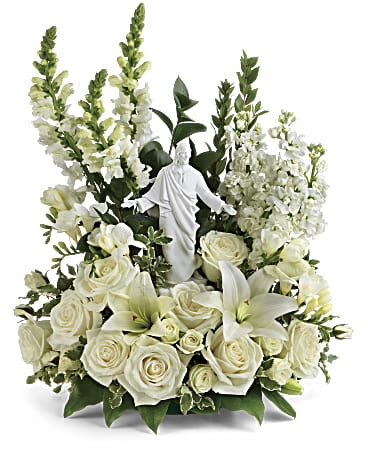 All-white arrangement of roses, lilies, and snapdragons surrounding a white Jesus figurine