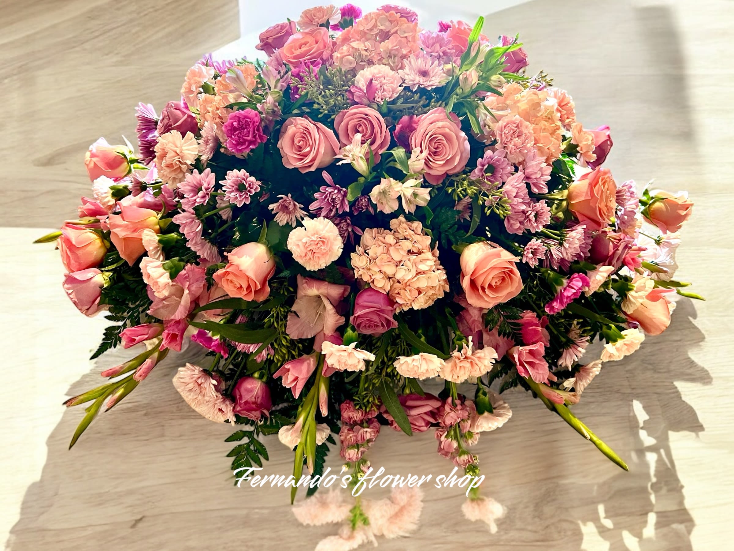 Low dome of pink and peach roses, carnations, and mums in a lush rounded centerpiece