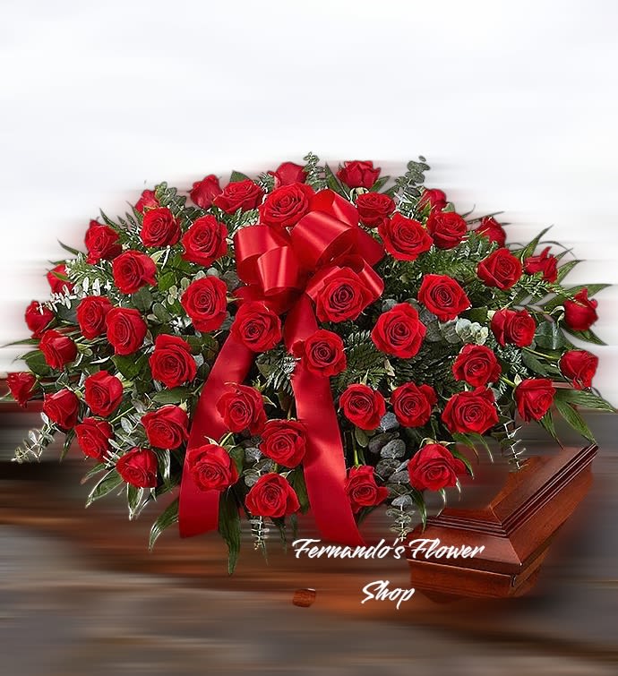 Red rose casket spray with a large red bow on a wooden casket