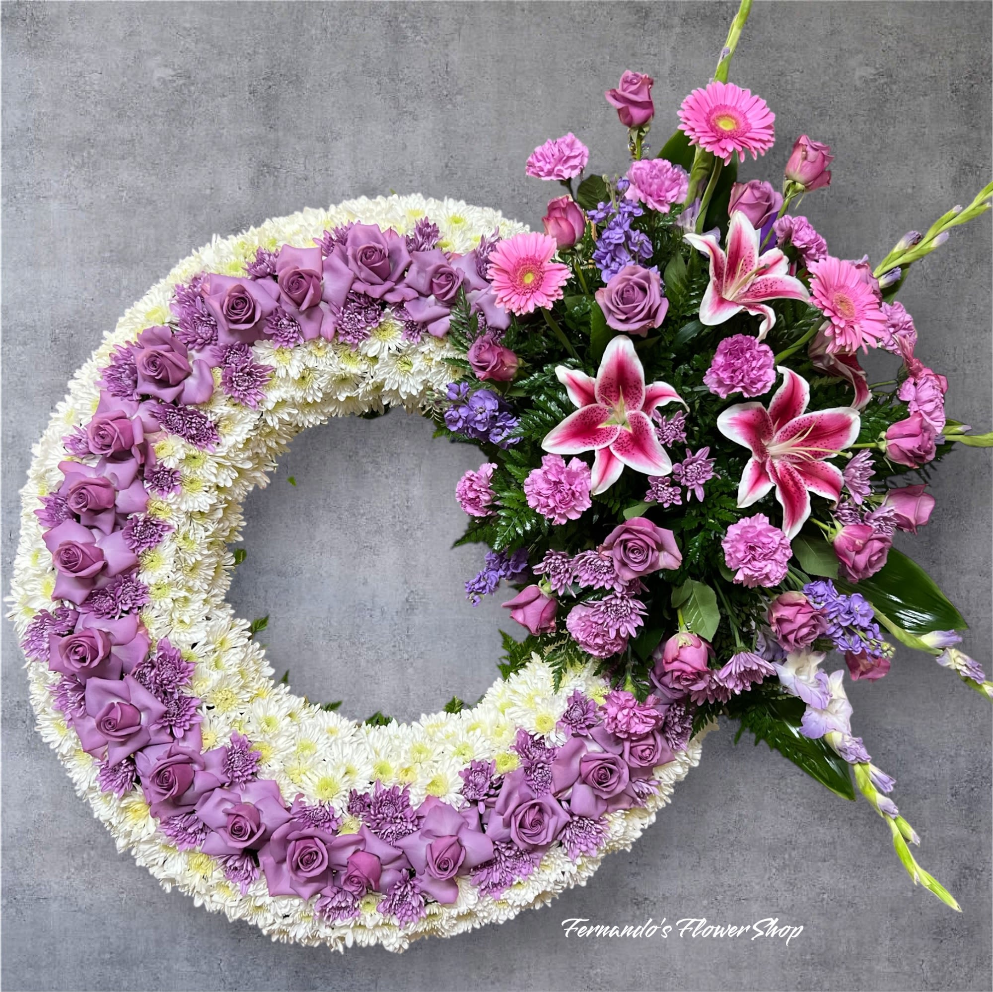 Large lavender and white wreath with a side cluster of pink lilies, roses, and carnations