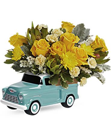 Yellow roses and white flowers arranged in a turquoise pickup truck container