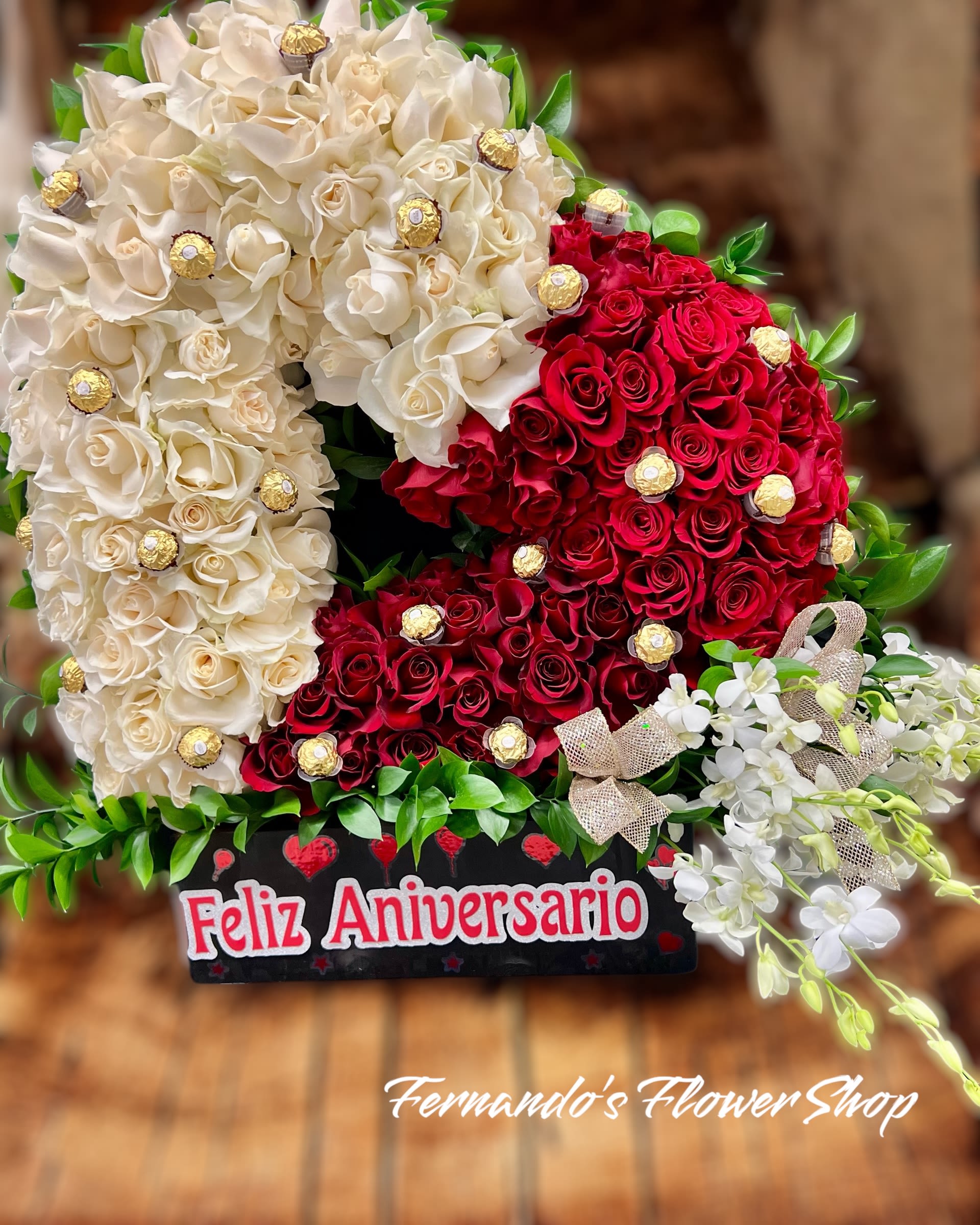 Heart-shaped arrangement of cream and red roses with chocolates and white orchids in an anniversary box