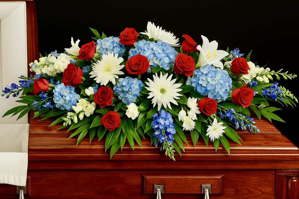 Red, white, and blue casket spray on a polished wooden casket