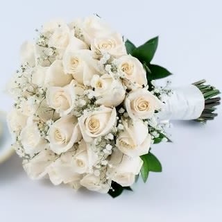 Hand-tied bouquet of white roses and baby's breath wrapped in white ribbon