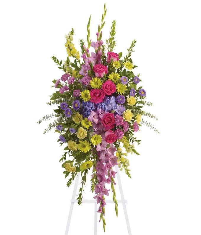 Tall standing spray of pink, yellow, and purple flowers on a white easel