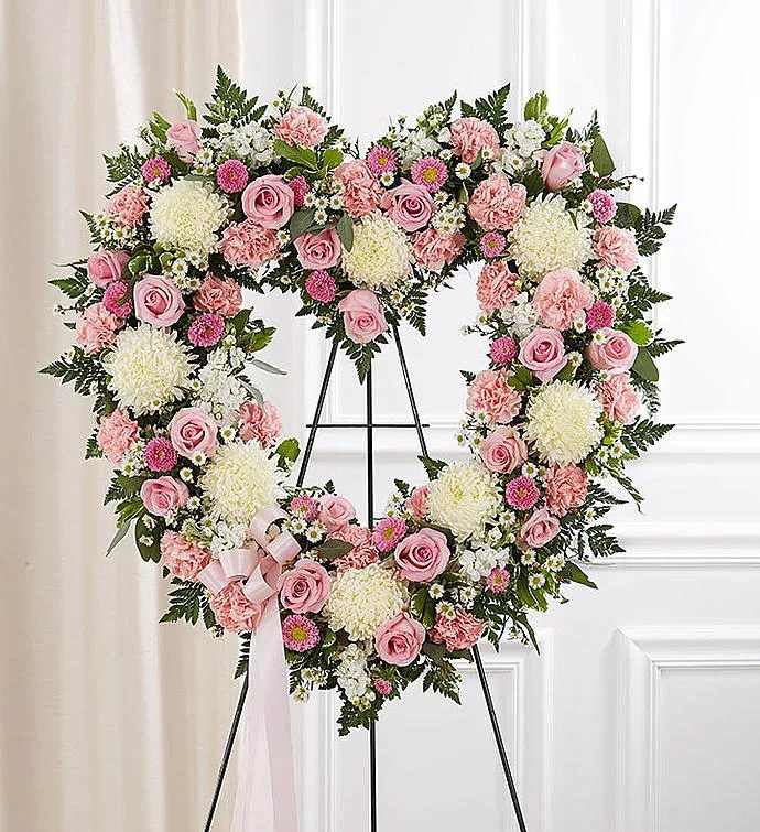 Heart-shaped standing wreath of pink and white flowers on a metal easel