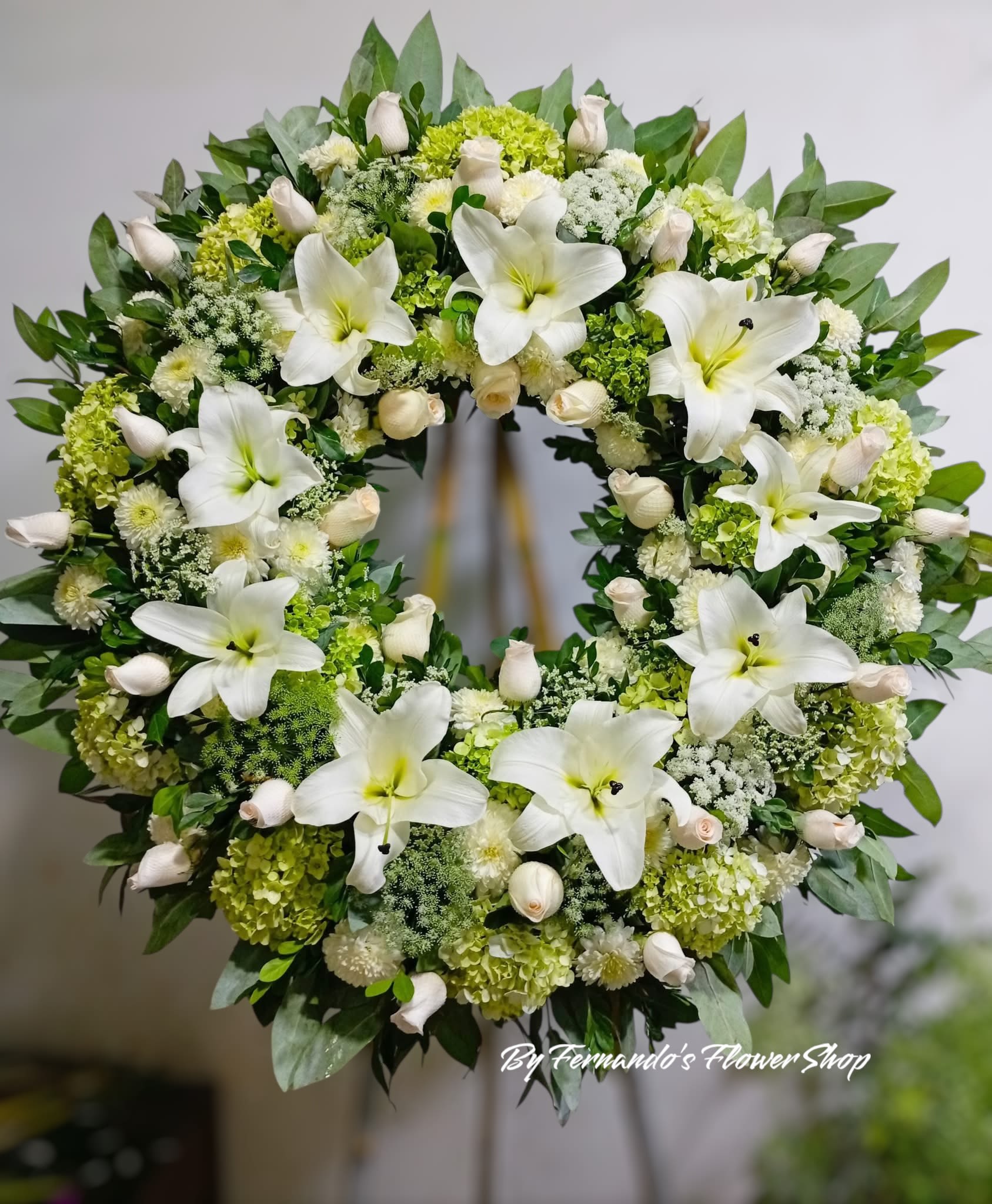 Large standing wreath of white lilies, roses, and hydrangeas on an easel