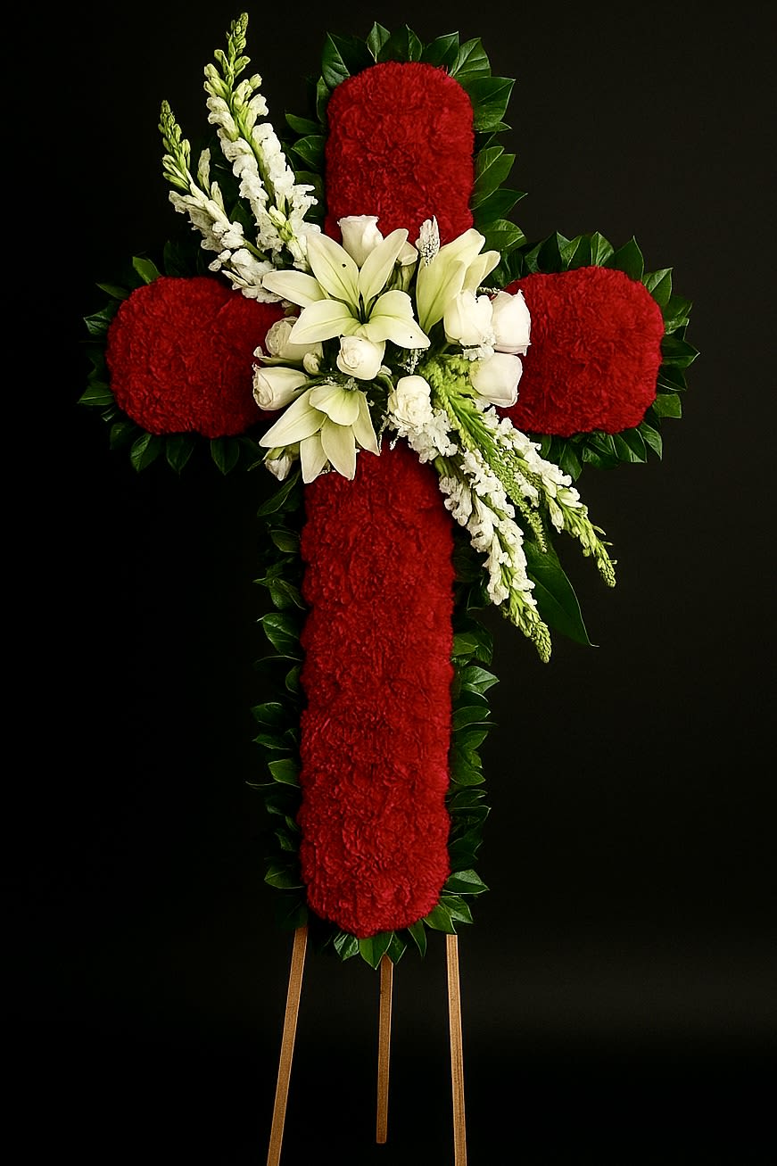 Standing red floral cross with white lilies and roses on a wooden easel