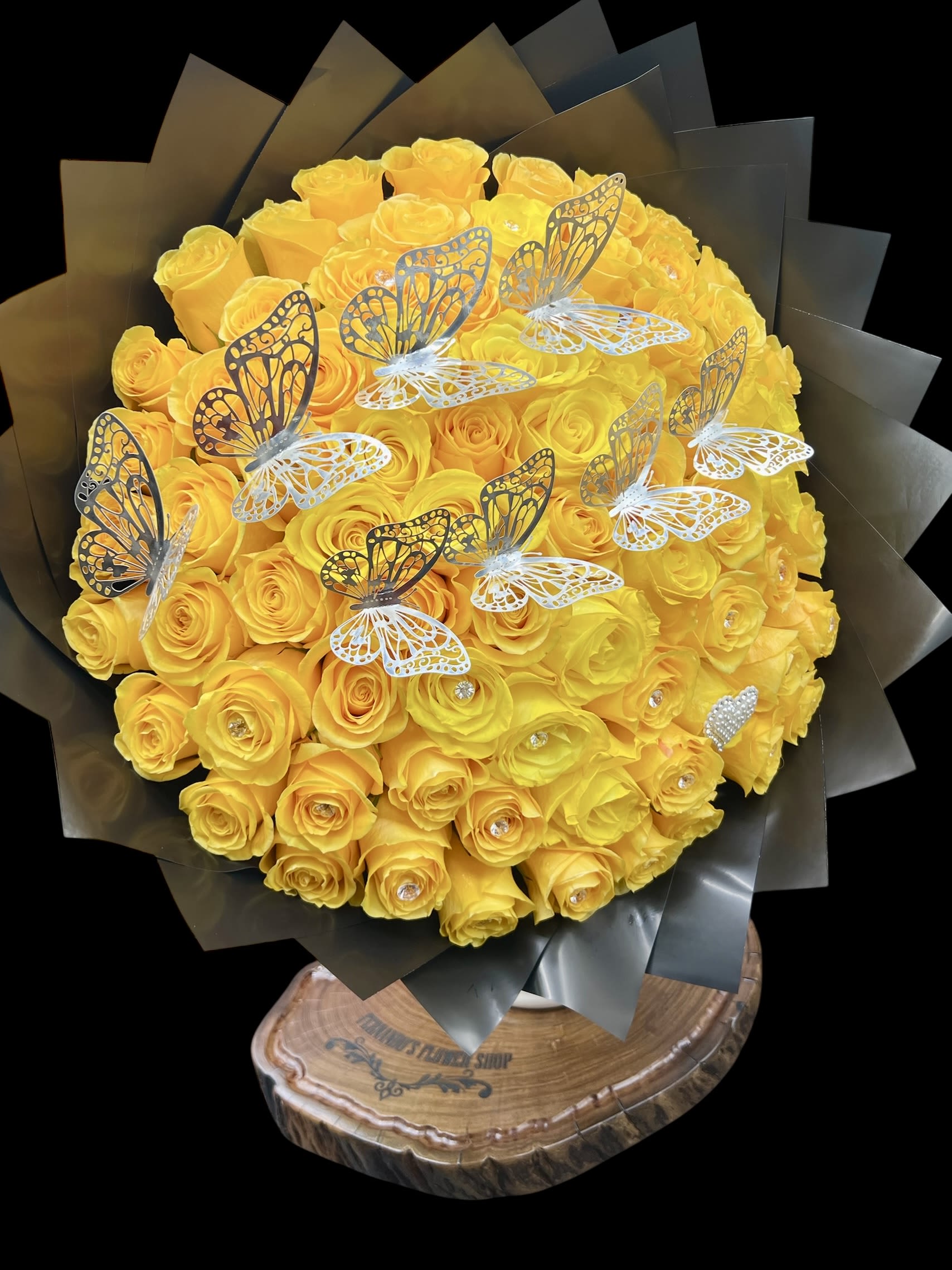 Pretty Face - A breathtaking bouquet of vibrant yellow roses adorned with delicate silver butterflies, creating a radiant and joyful display full of elegance and charm. Perfect for brightening someone’s day, celebrating milestones, or making any occasion unforgettable with its dazzling color and graceful details.  75 Roses. Can Be Done Any Color. 