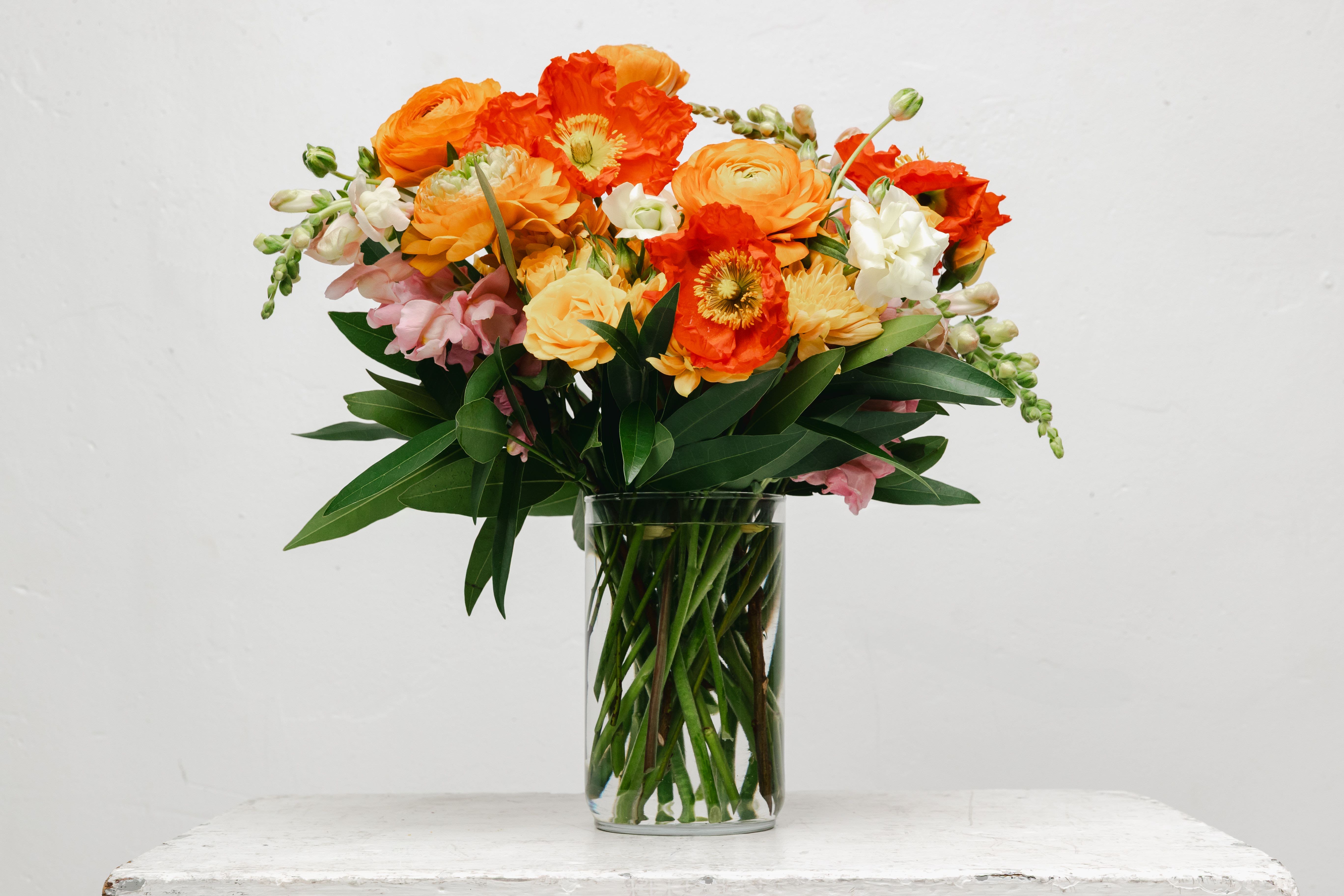 Orange and pink mixed bouquet in a clear glass vase
