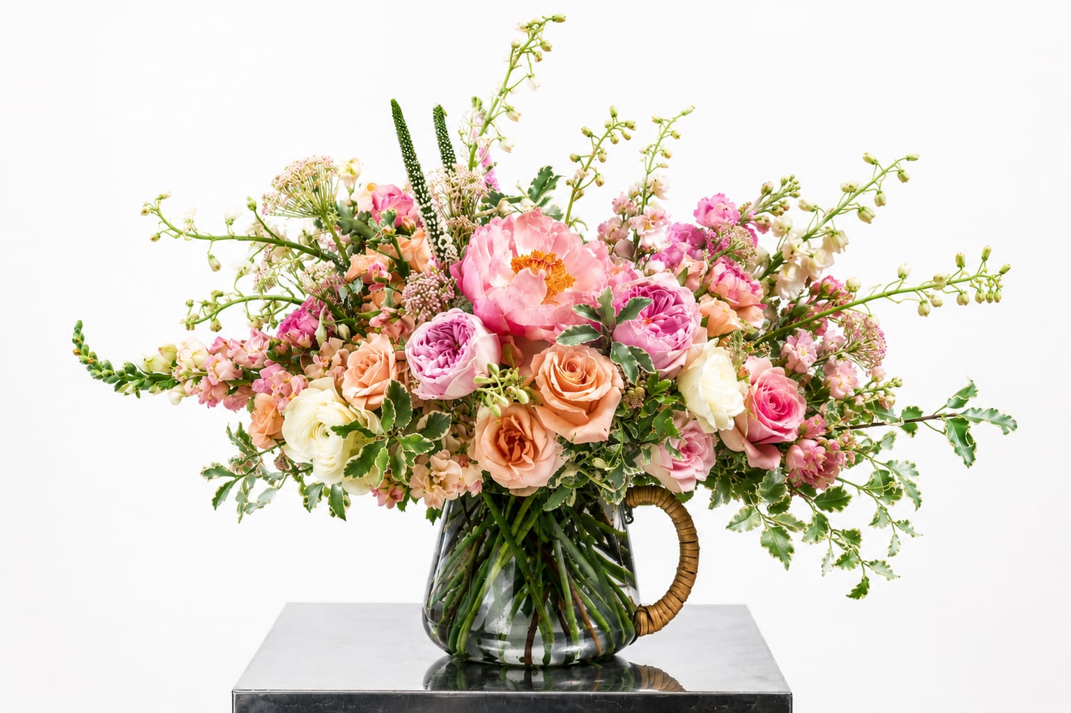 Pink and peach mixed flower arrangement in a glass pitcher vase