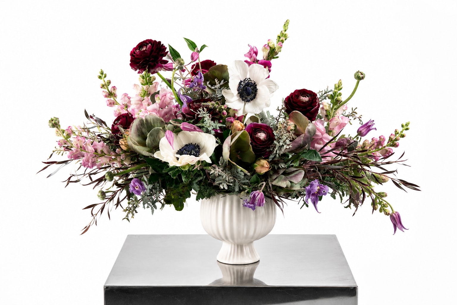 Large mixed floral arrangement in a white pedestal vase