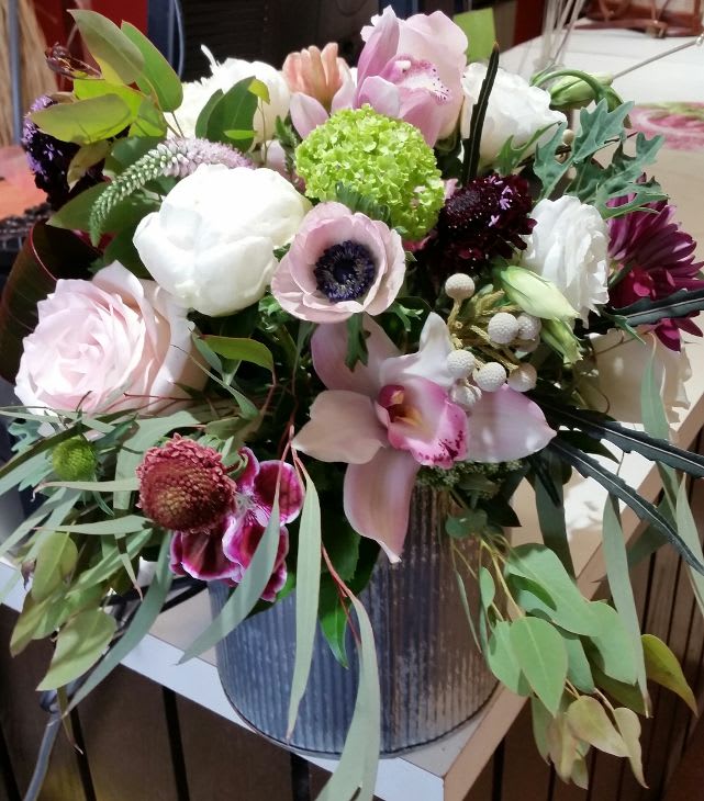 Mixed bouquet of pink, white, and green flowers in a metal vase