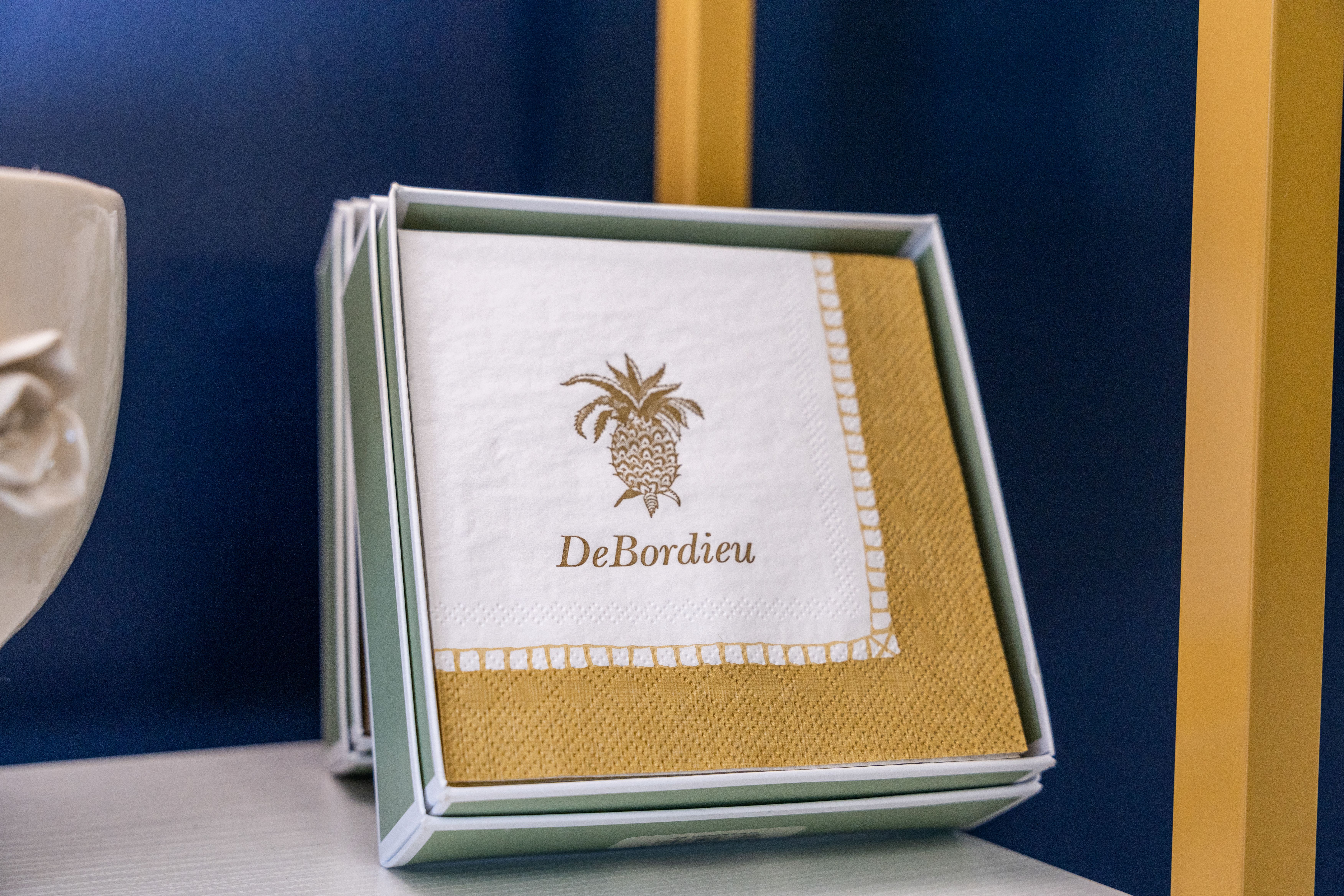 Boxed napkins with a gold pineapple logo and trim
