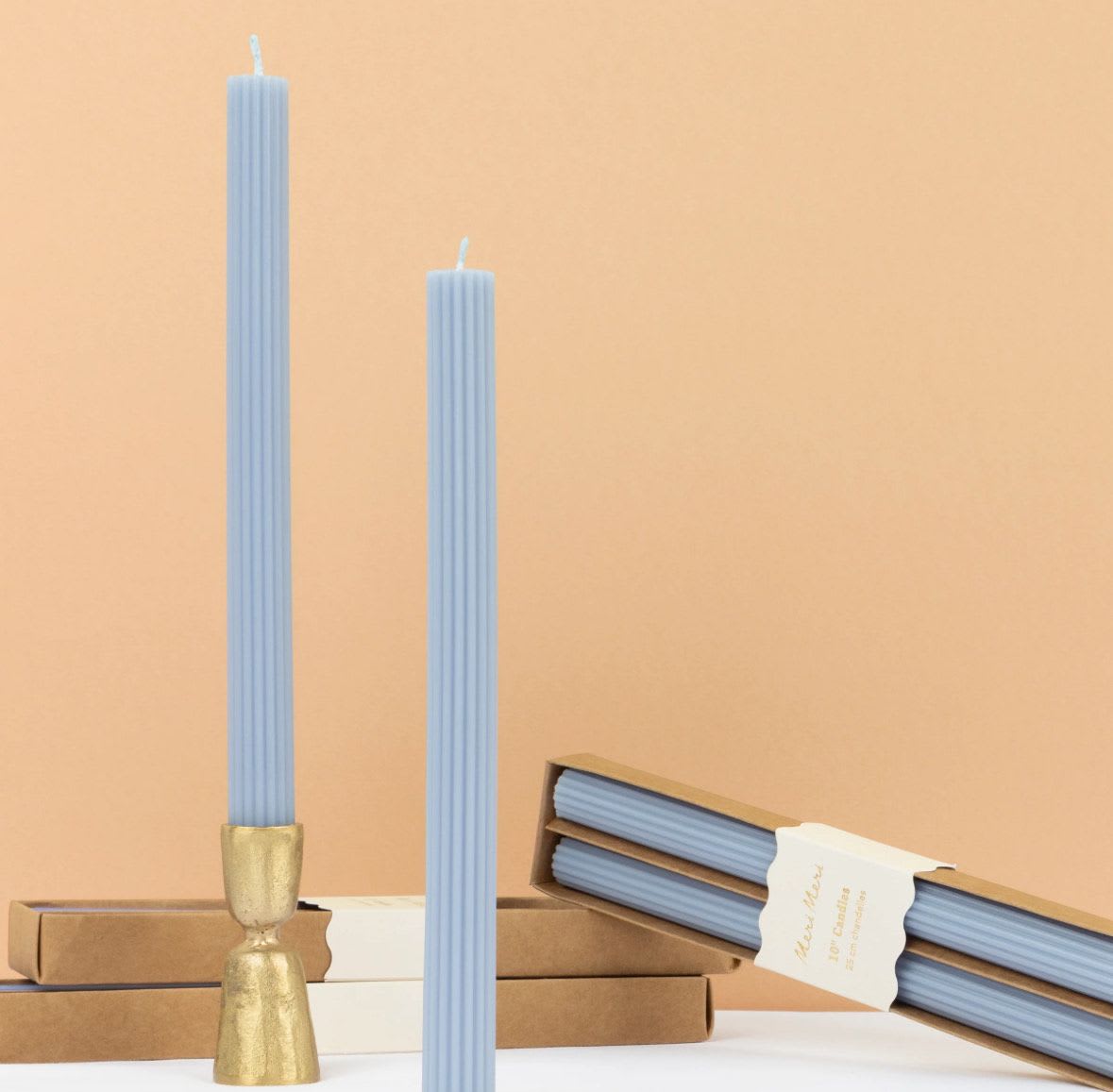 Two light blue ribbed taper candles with boxes and a gold holder