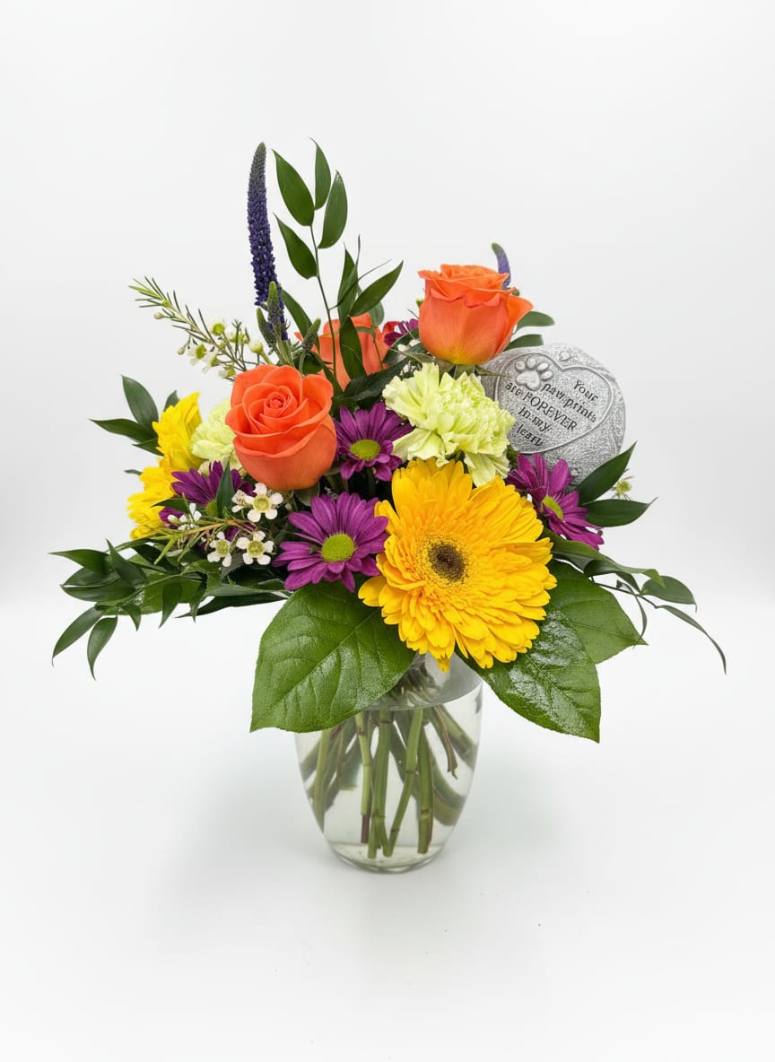 Mixed bouquet with orange roses, yellow gerbera daisies, and purple flowers in a glass vase