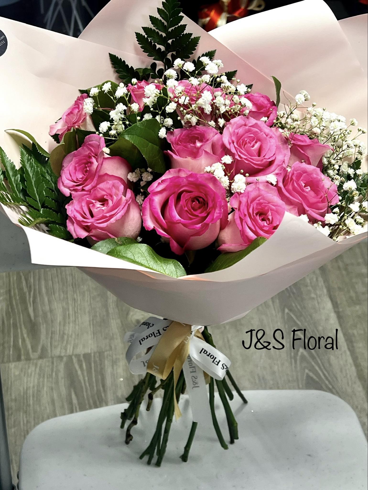 Bouquet of pink roses with baby's breath wrapped in pale paper