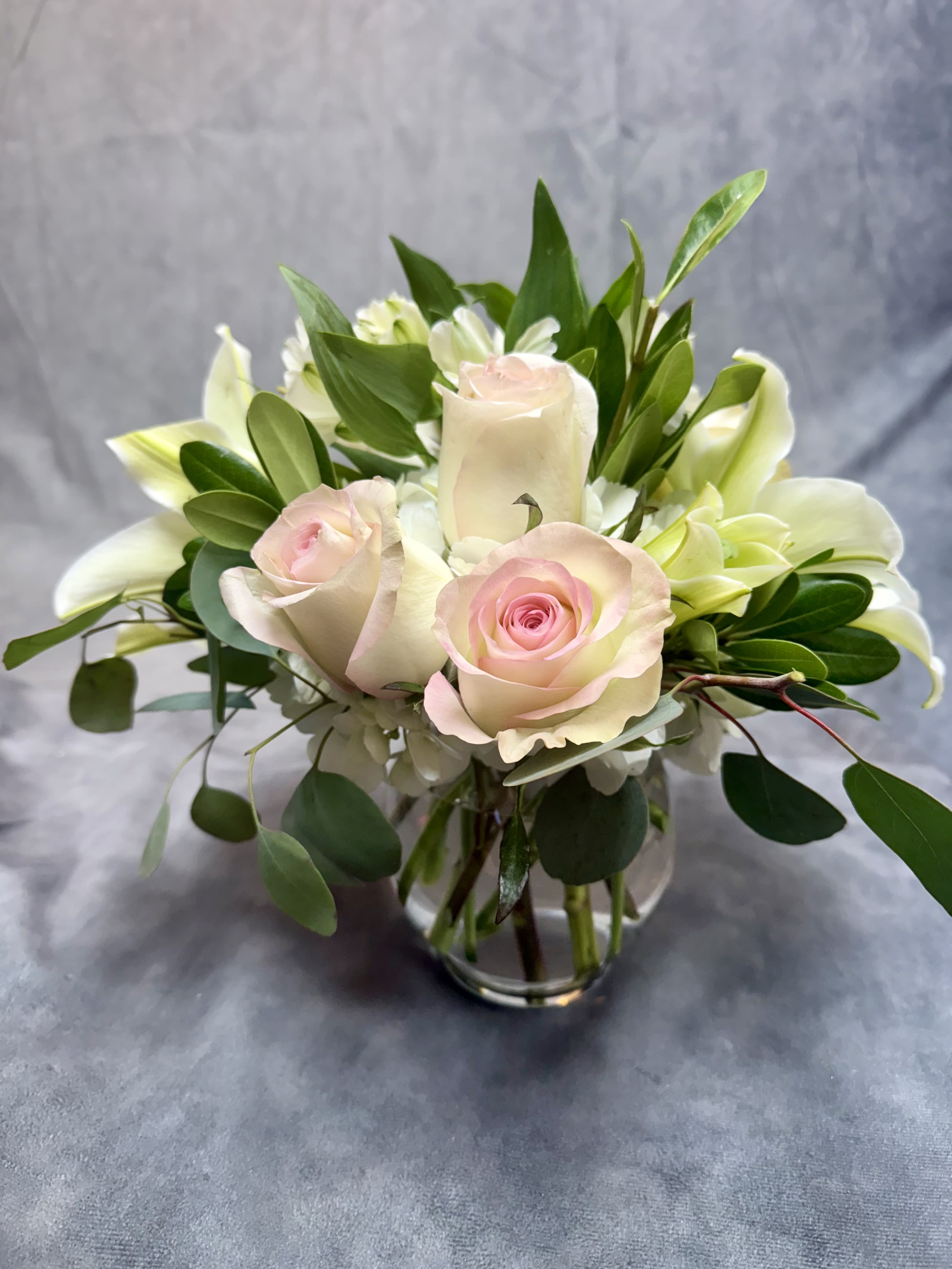 Pink roses and white lilies arranged in a clear glass vase