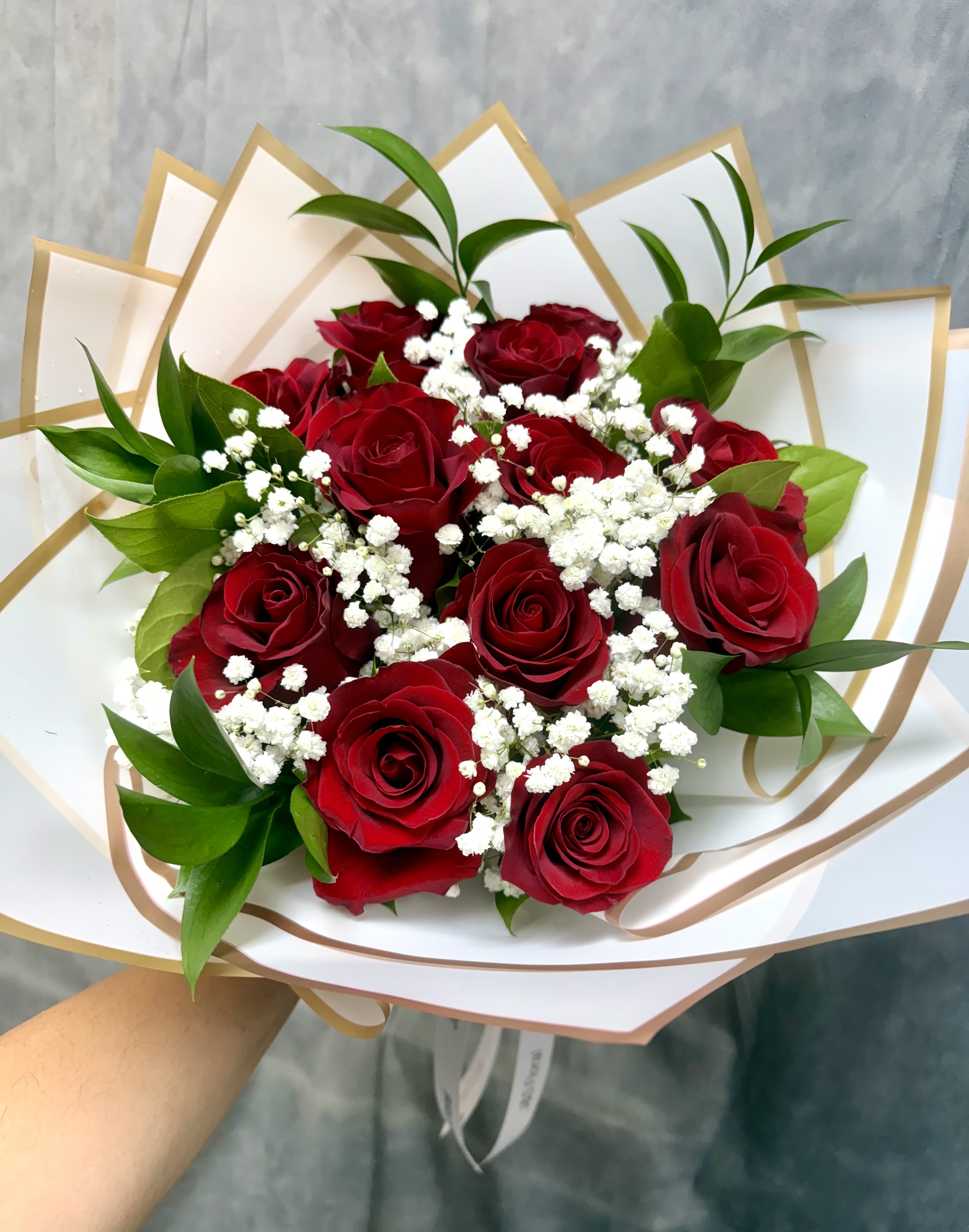 Bouquet of red roses with white baby's breath in white and gold wrap
