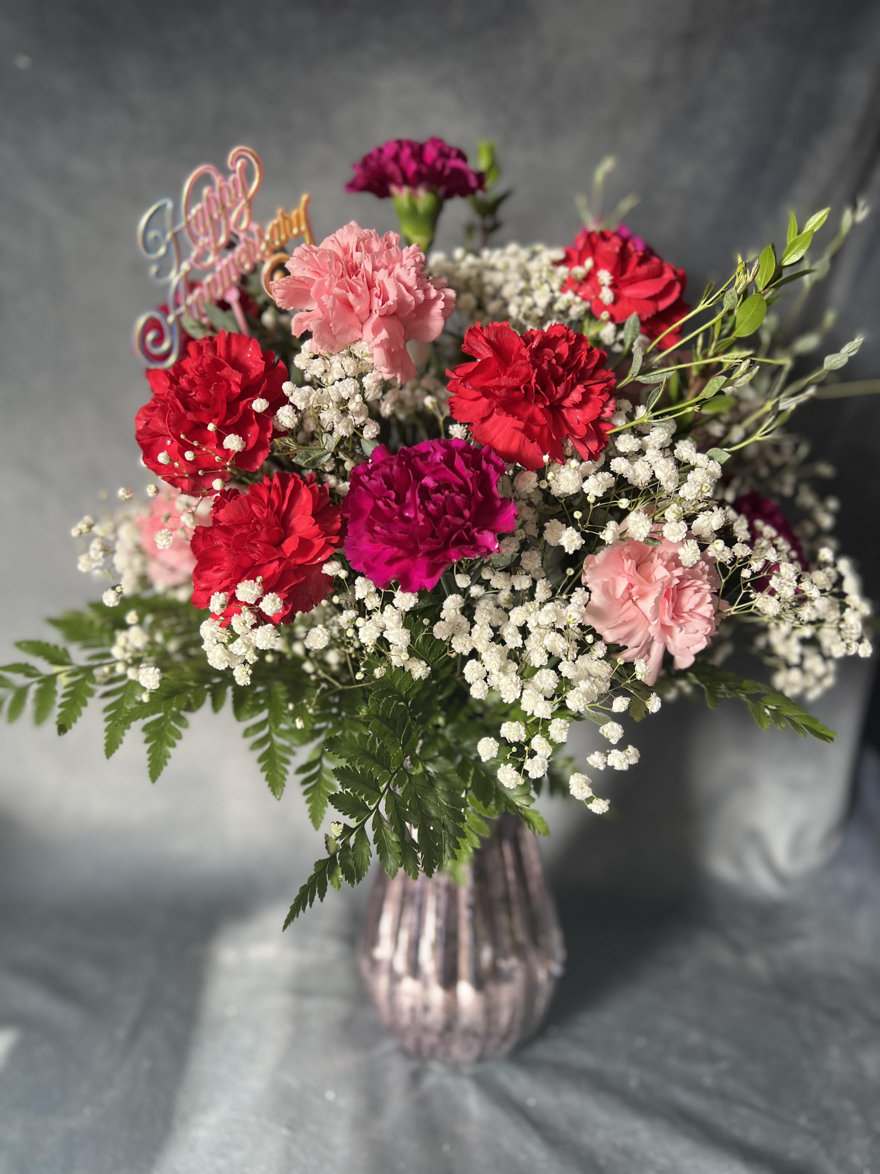 Bouquet of pink and red carnations with baby's breath in a glass vase