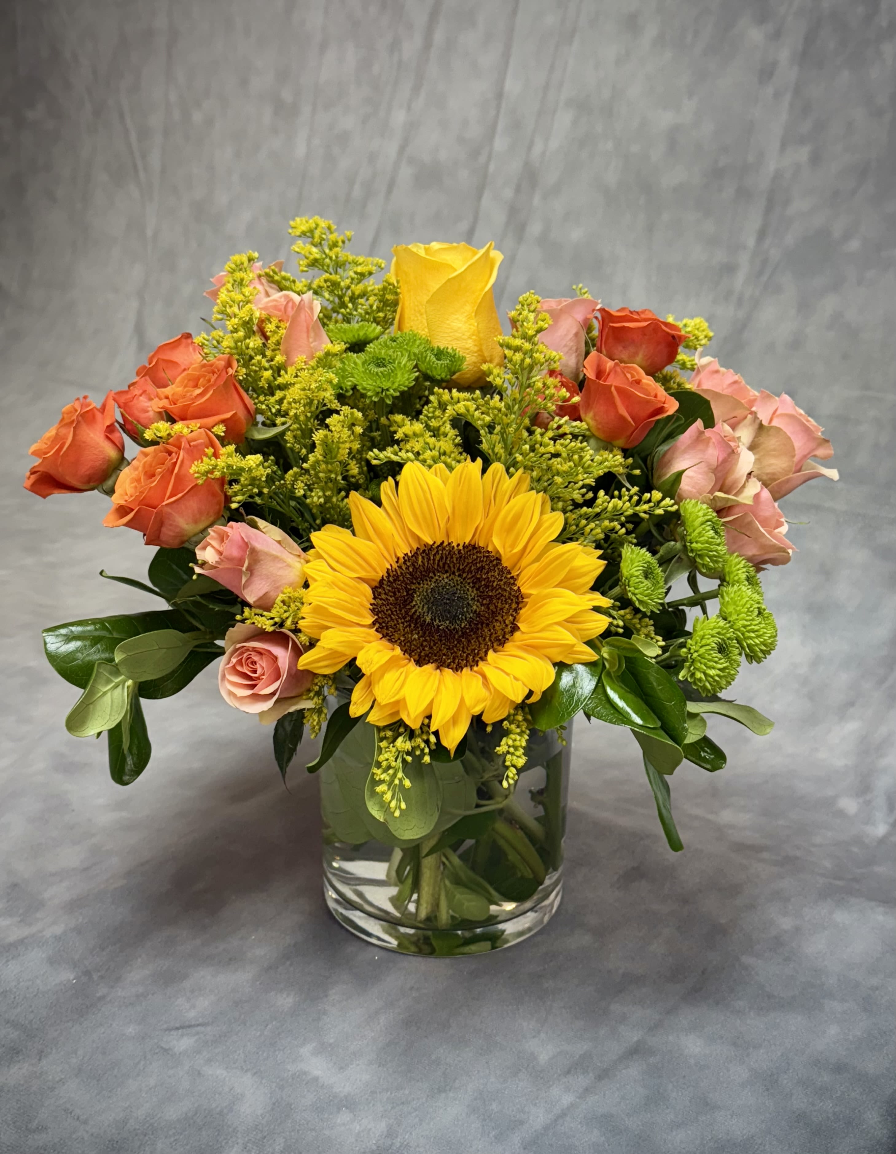 Bouquet of sunflowers and roses in a clear glass vase
