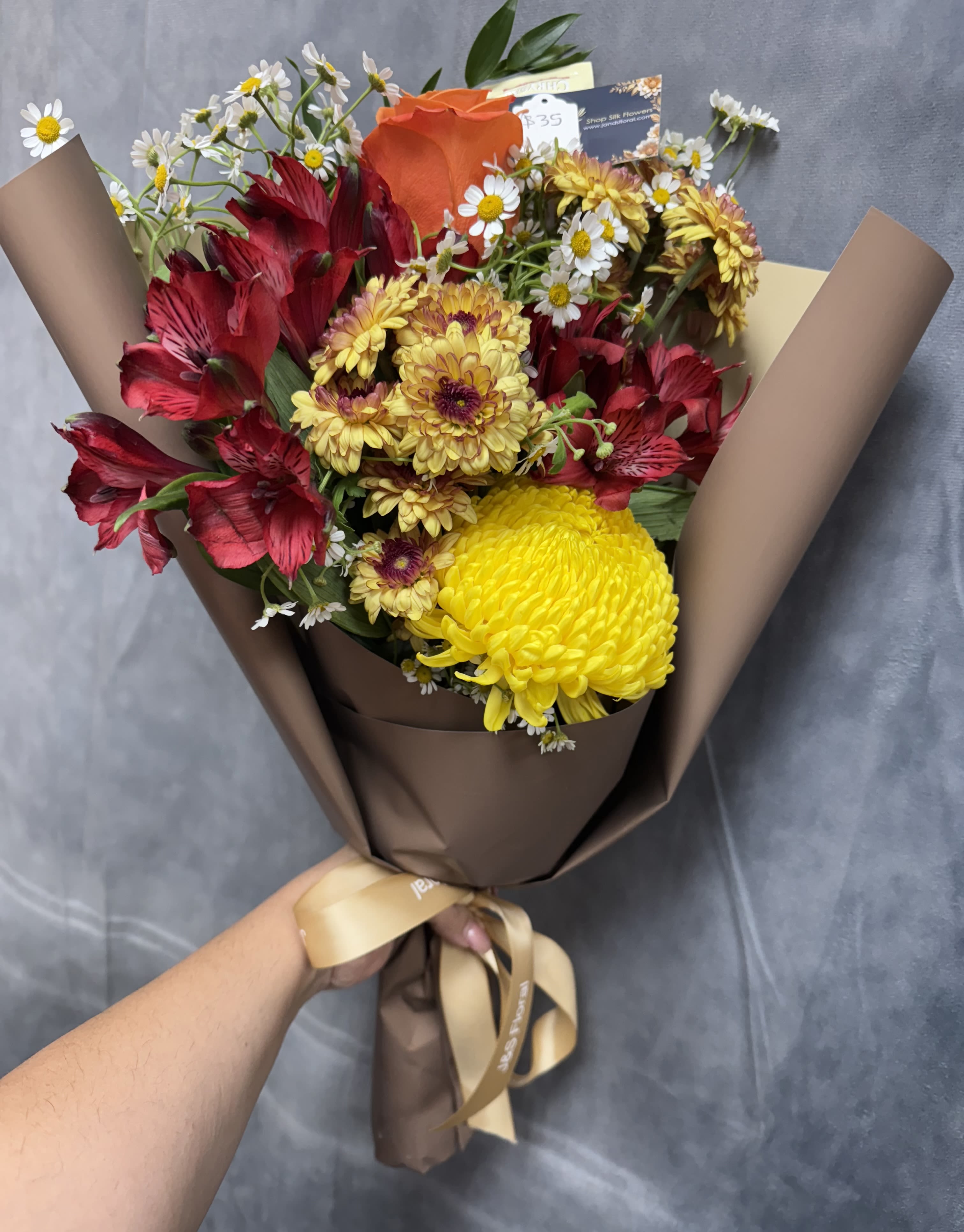 Fall bouquet  - A charming hand-tied fall bouquet featuring mums, alstroemeria, roses, and button poms in rich seasonal hues of orange, yellow, and burgundy — perfectly capturing the warmth and beauty of autumn.