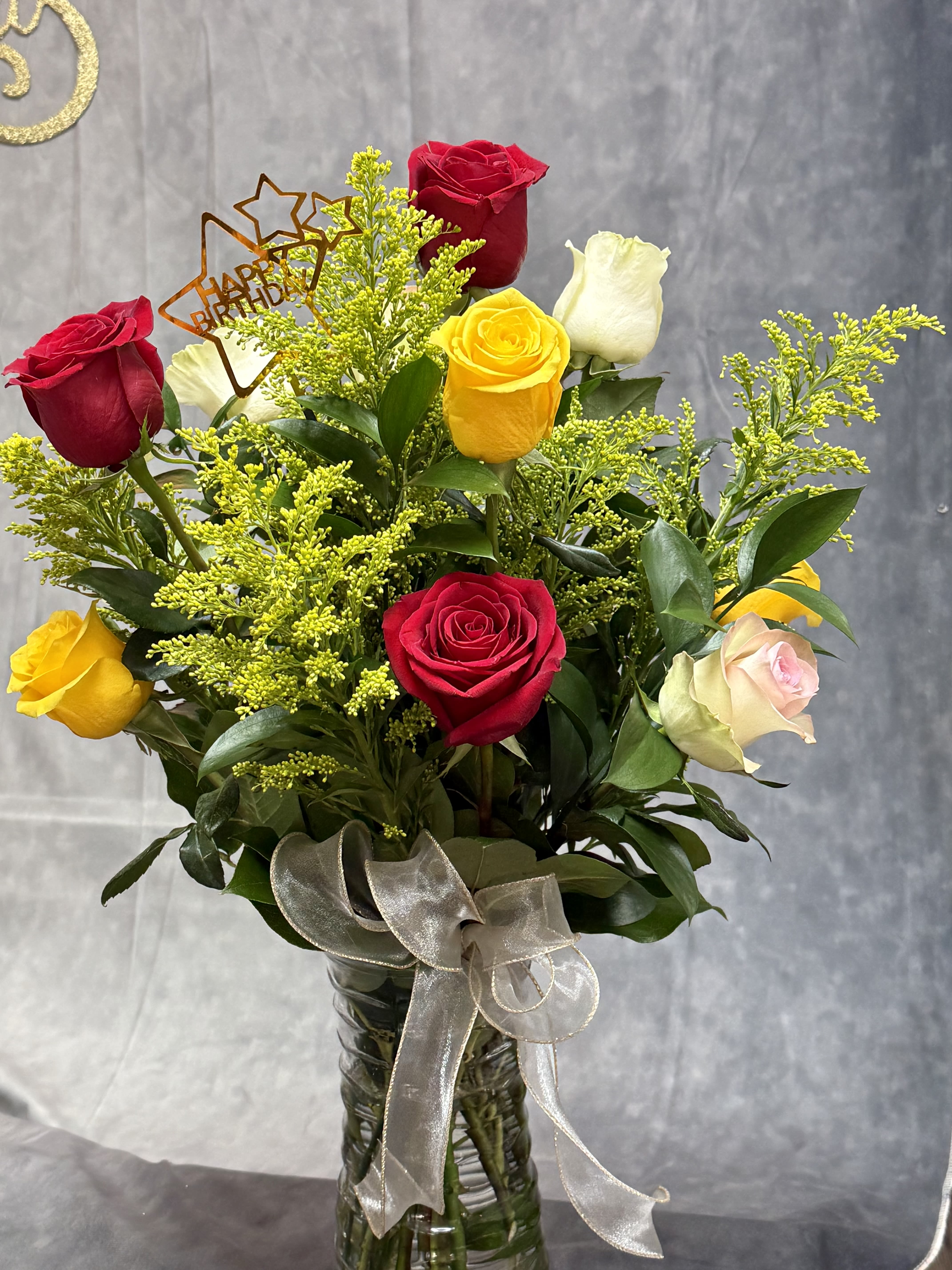 Bouquet of red, yellow, white, and pink roses in a glass vase