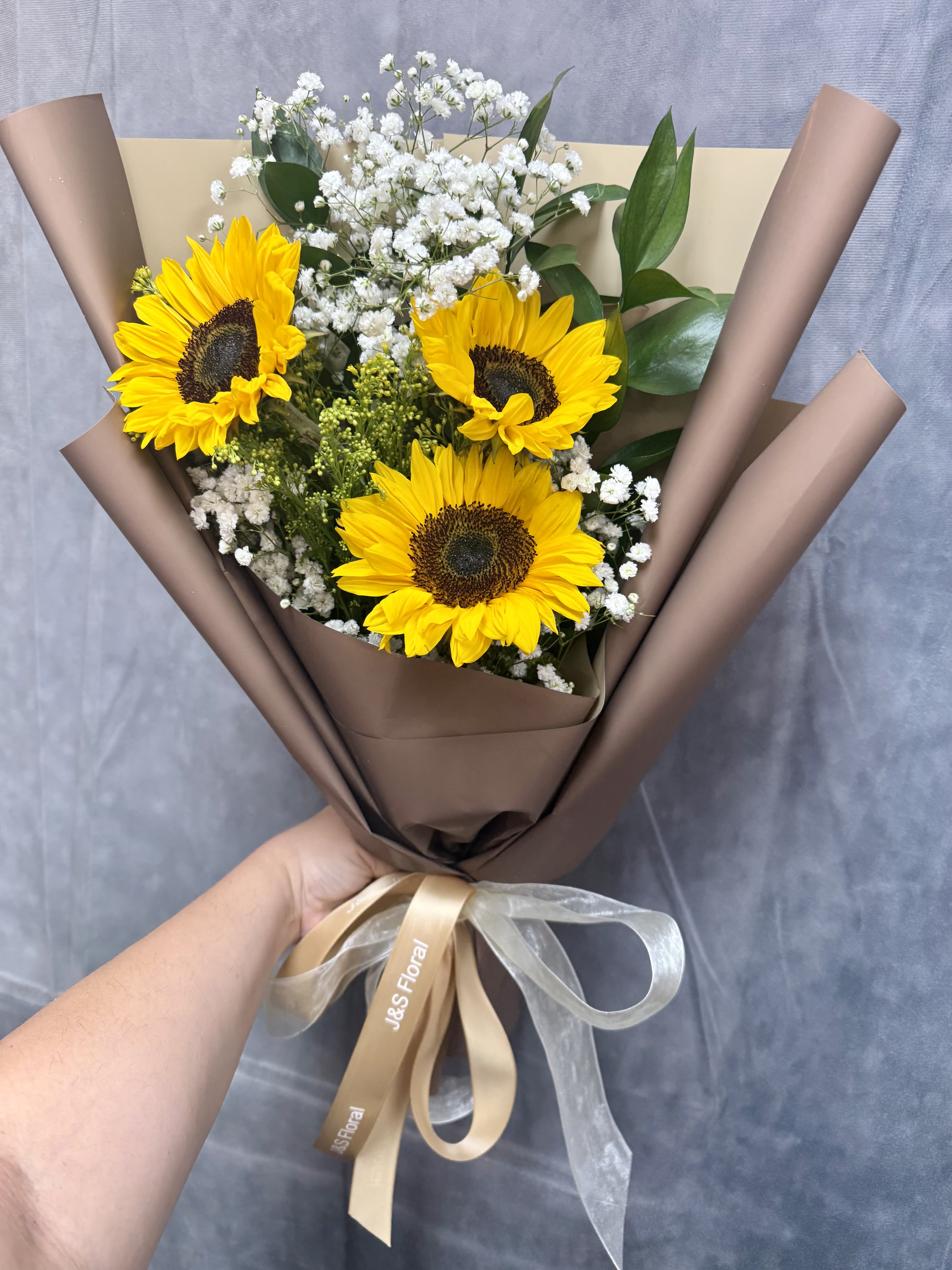 Bouquet of sunflowers and white baby's breath wrapped in brown paper