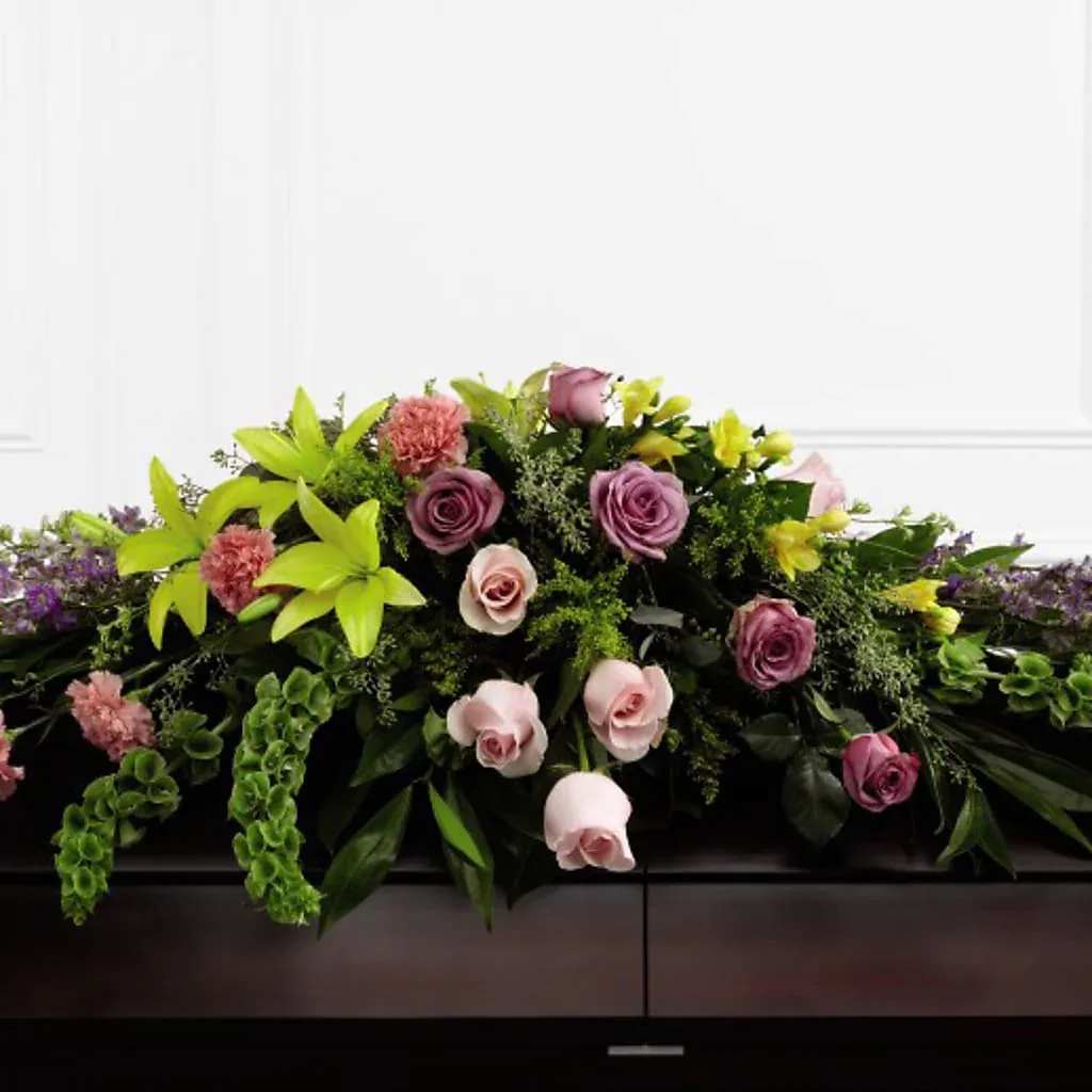 Casket spray with pink and lavender roses and bright green lilies